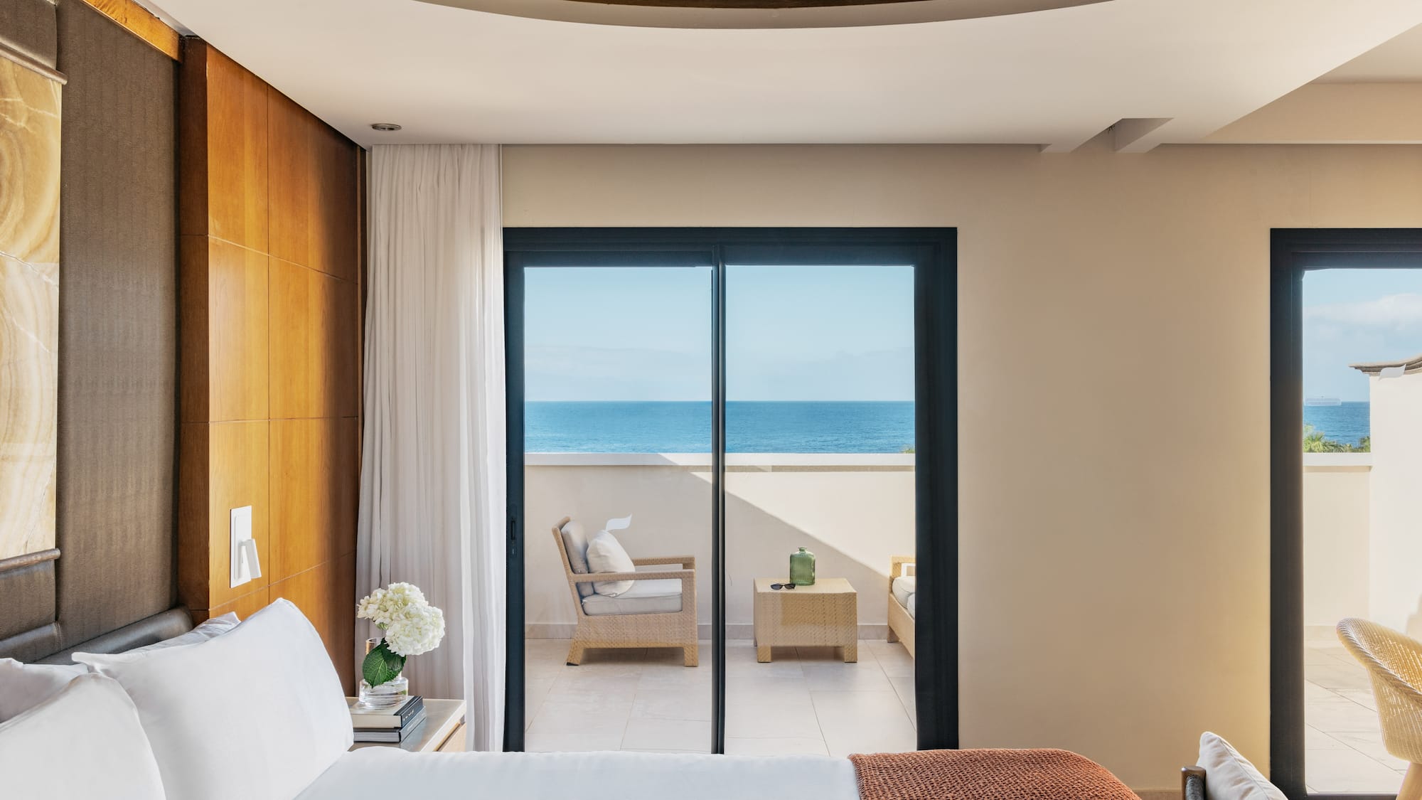 a bedroom with a glass door leading to the ocean