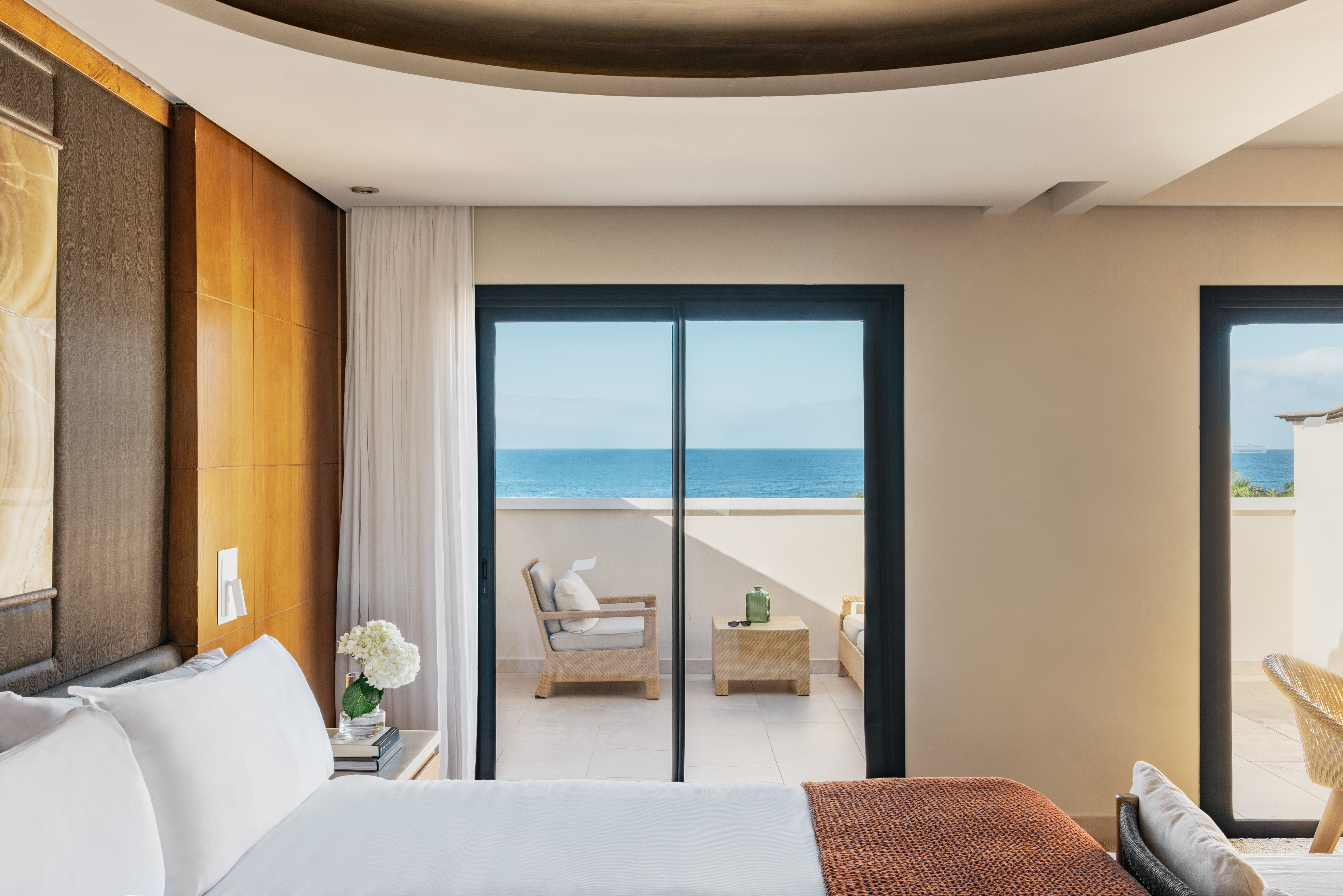 Modern hotel bedroom with ocean view balcony and comfortable bed.
