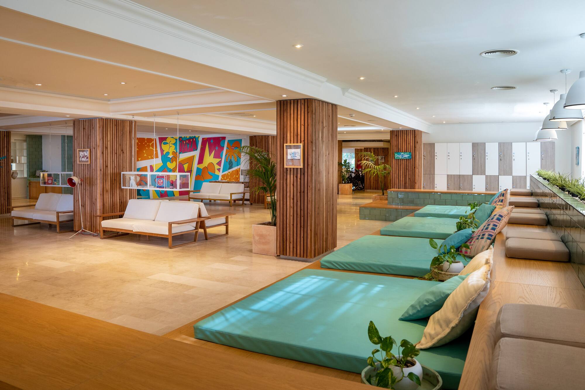 Modern resort lounge with turquoise daybeds, white sofas, and colorful art.
