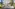 Sunny resort hotel with arched balconies, palm trees, and a paved entrance.