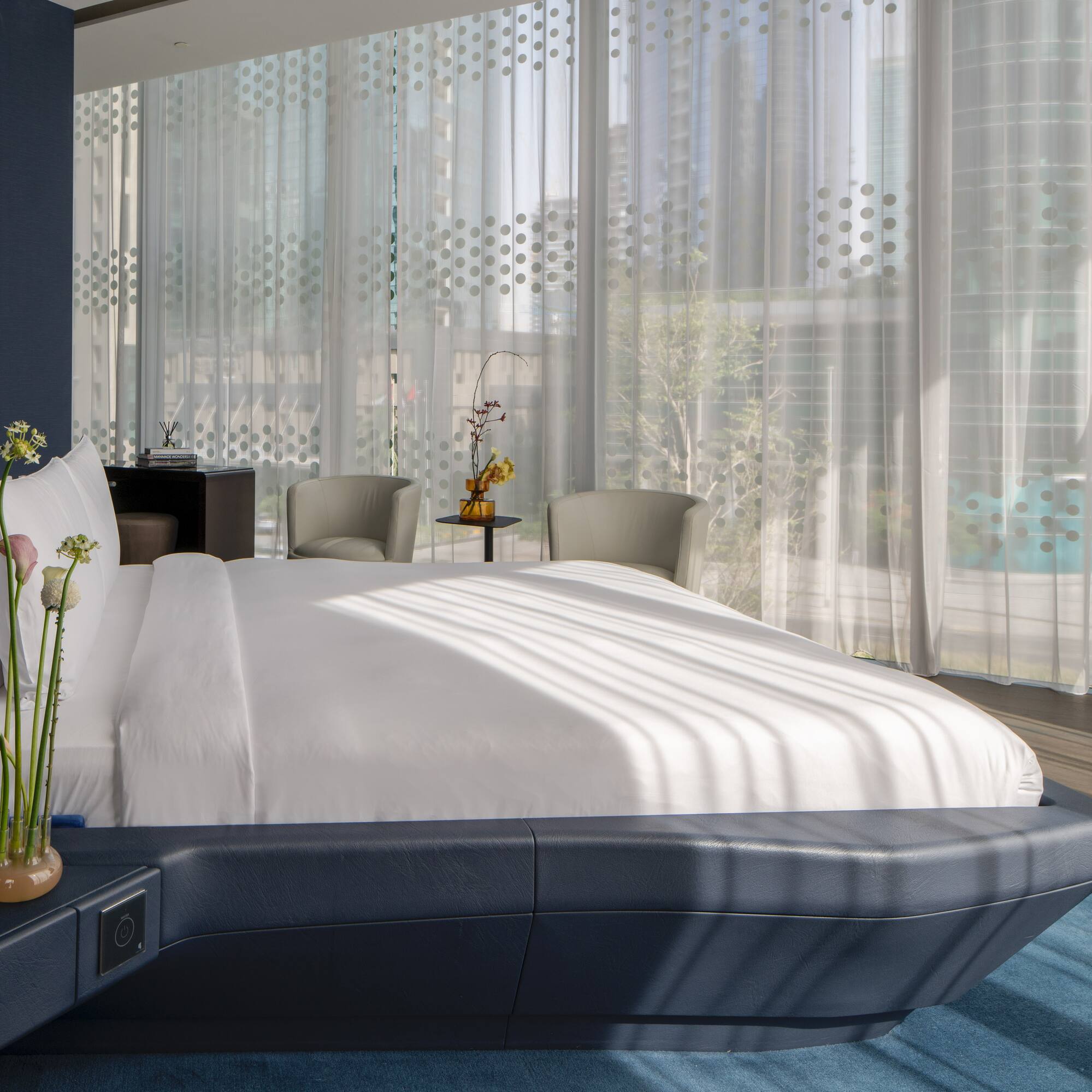 a bed with a white bed frame and a vase of flowers in front of a window