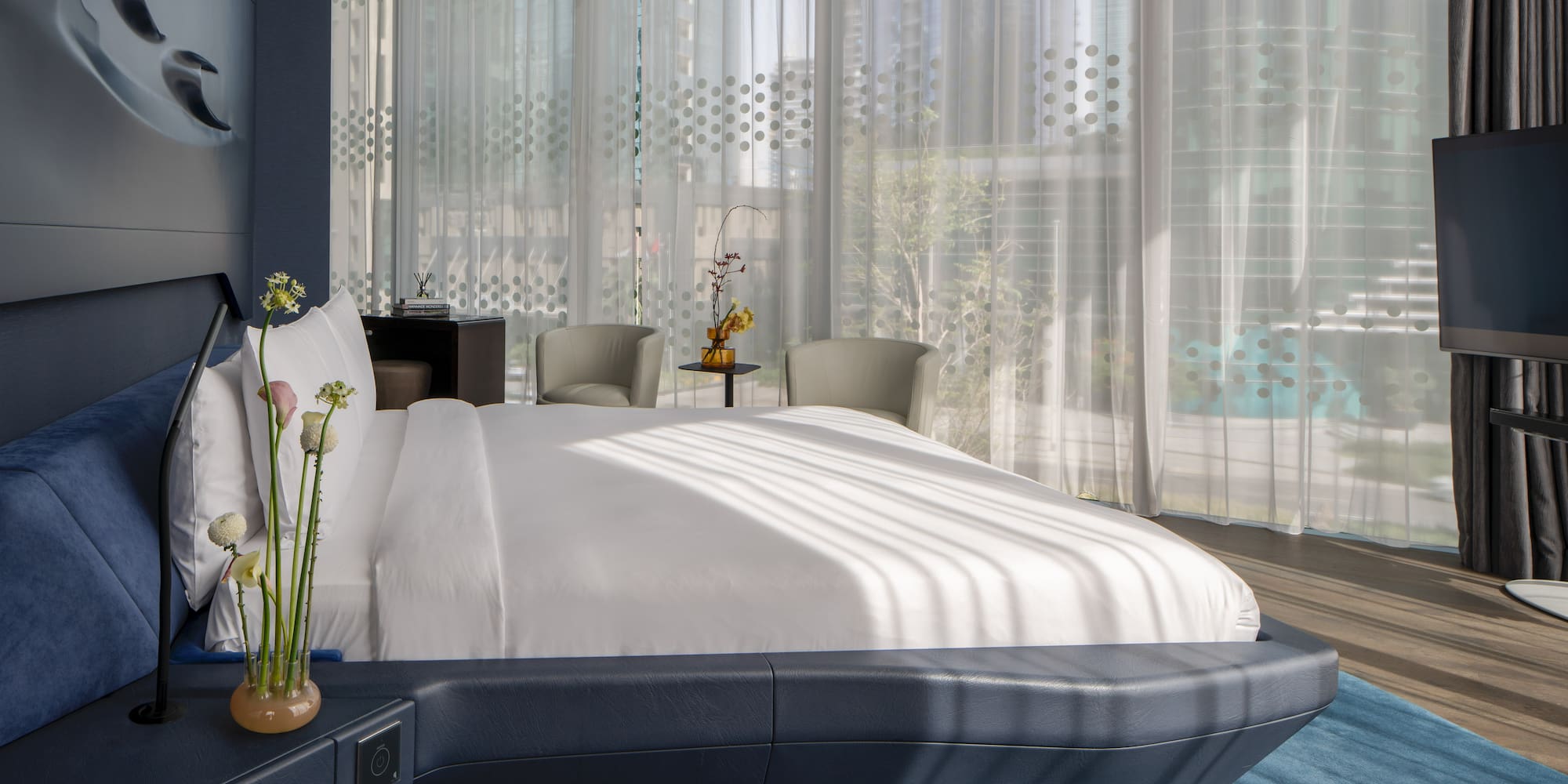 a bed with a white bed frame and a vase of flowers in front of a window