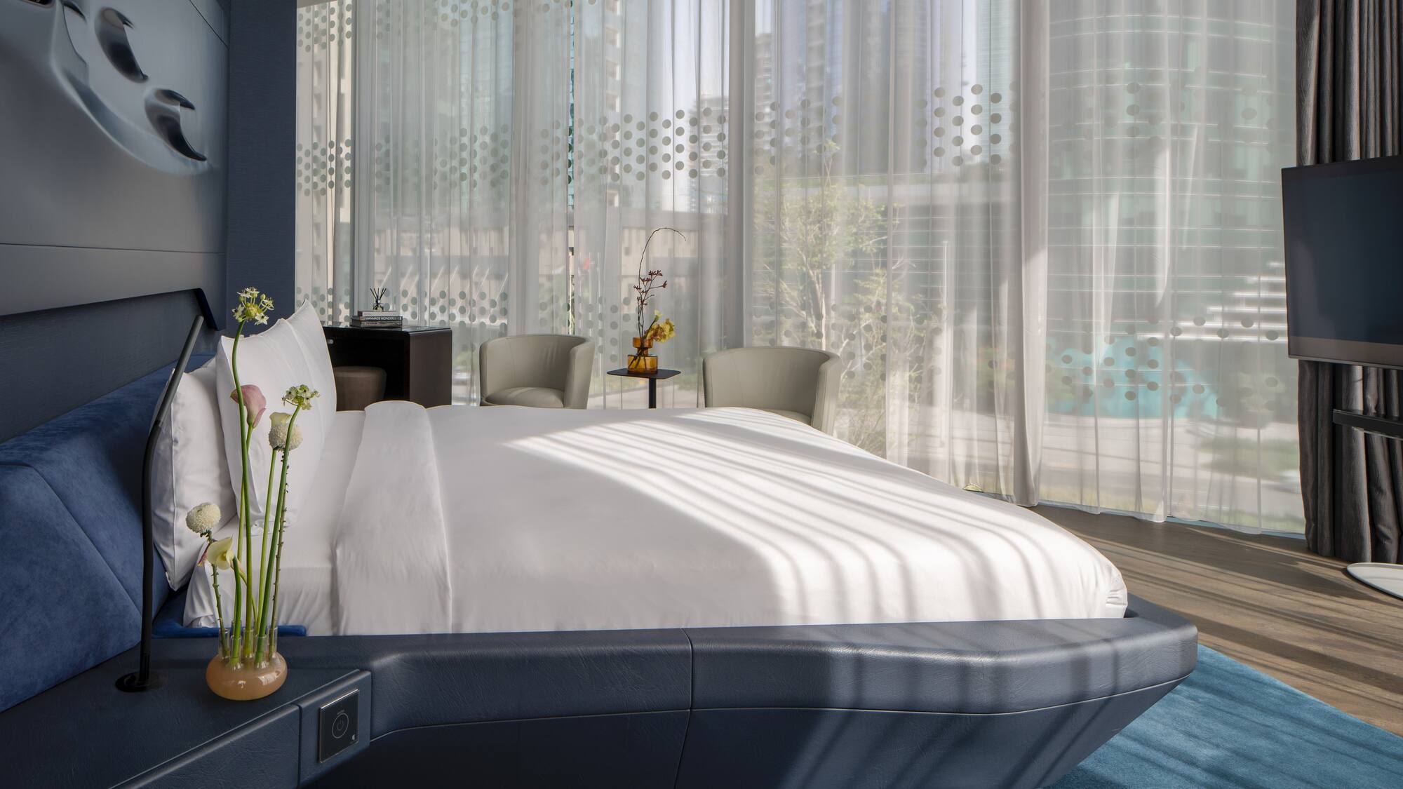 a bed with a white bed frame and a vase of flowers in front of a window