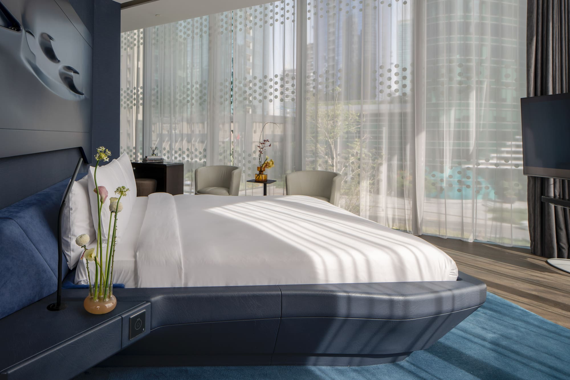 a bed with a white bed frame and a vase of flowers in front of a window