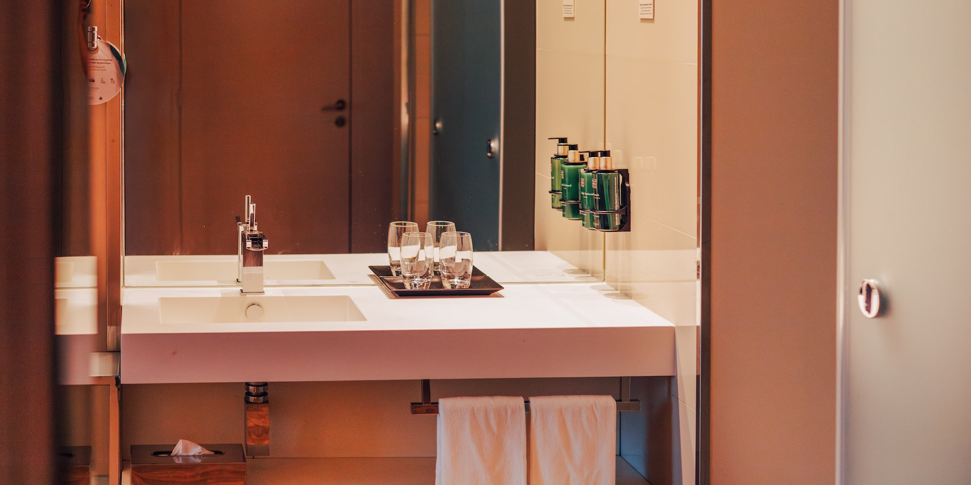 Modern hotel bathroom vanity with sink, mirror, and amenities.