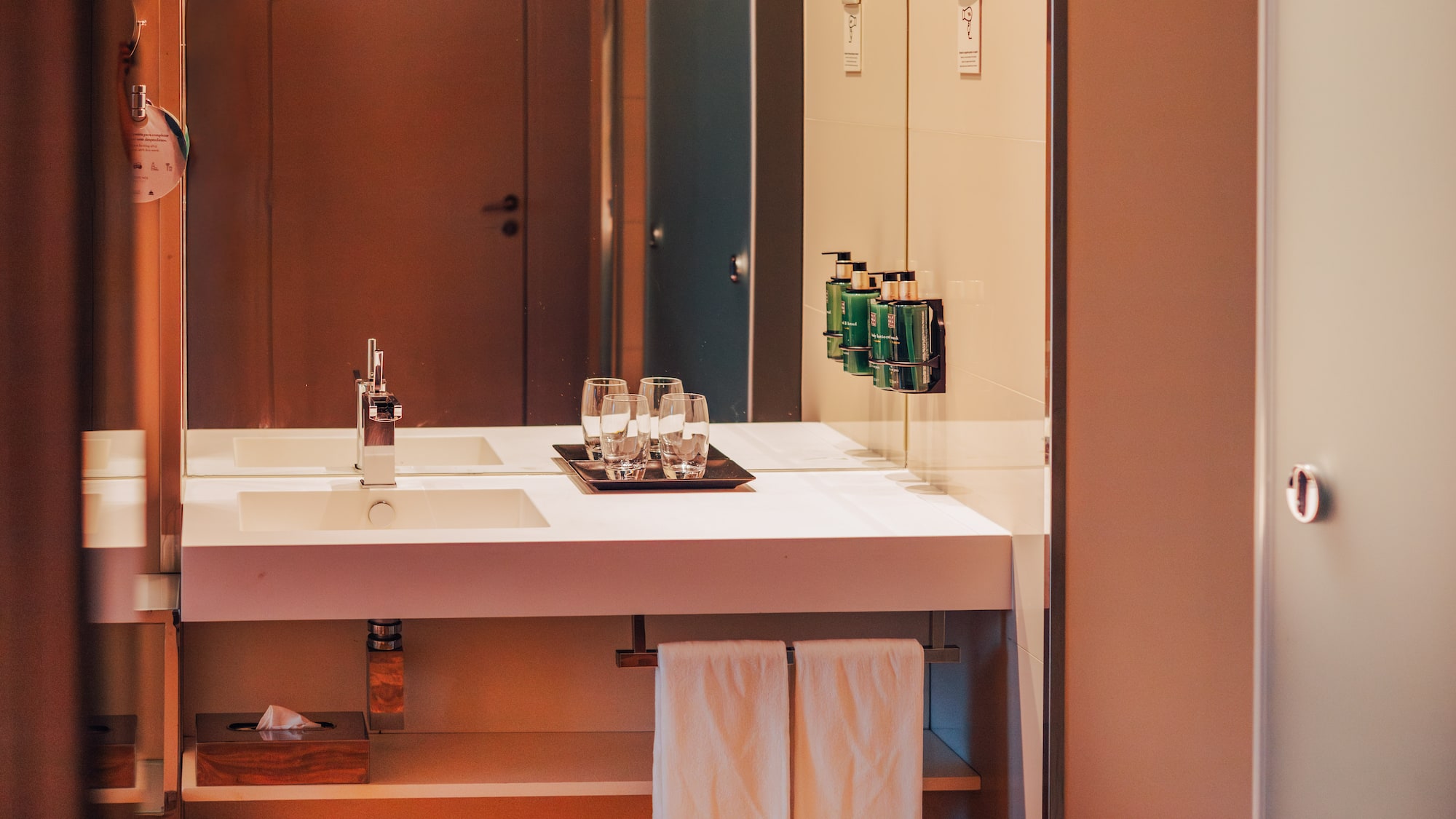 Modern hotel bathroom vanity with sink, mirror, and amenities.