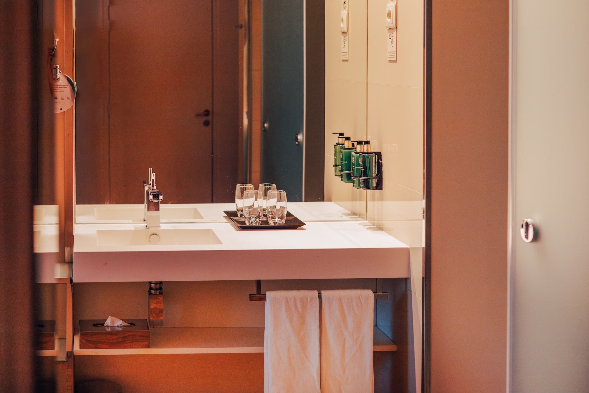 Modern hotel bathroom vanity with sink, mirror, and amenities.