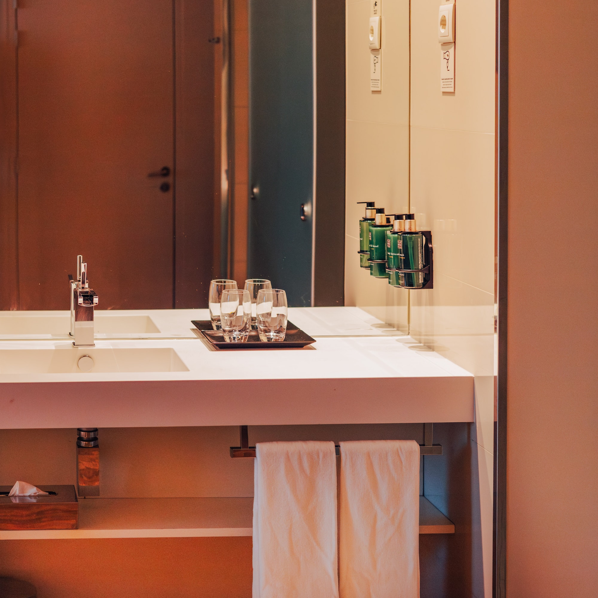 Modern hotel bathroom vanity with sink, mirror, and amenities.