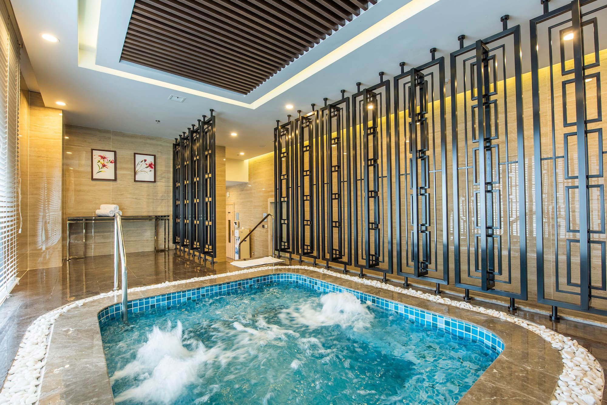 Modern indoor spa jacuzzi with bubbling water and decorative screens.