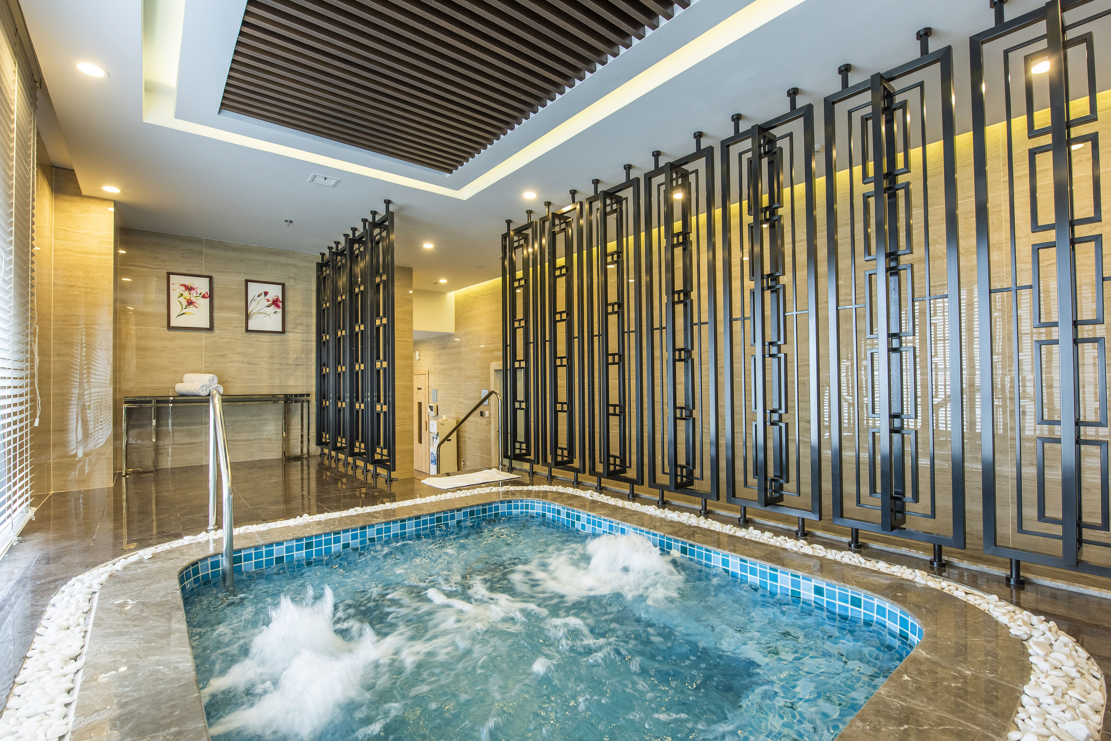 Modern indoor spa jacuzzi with bubbling water and decorative screens.