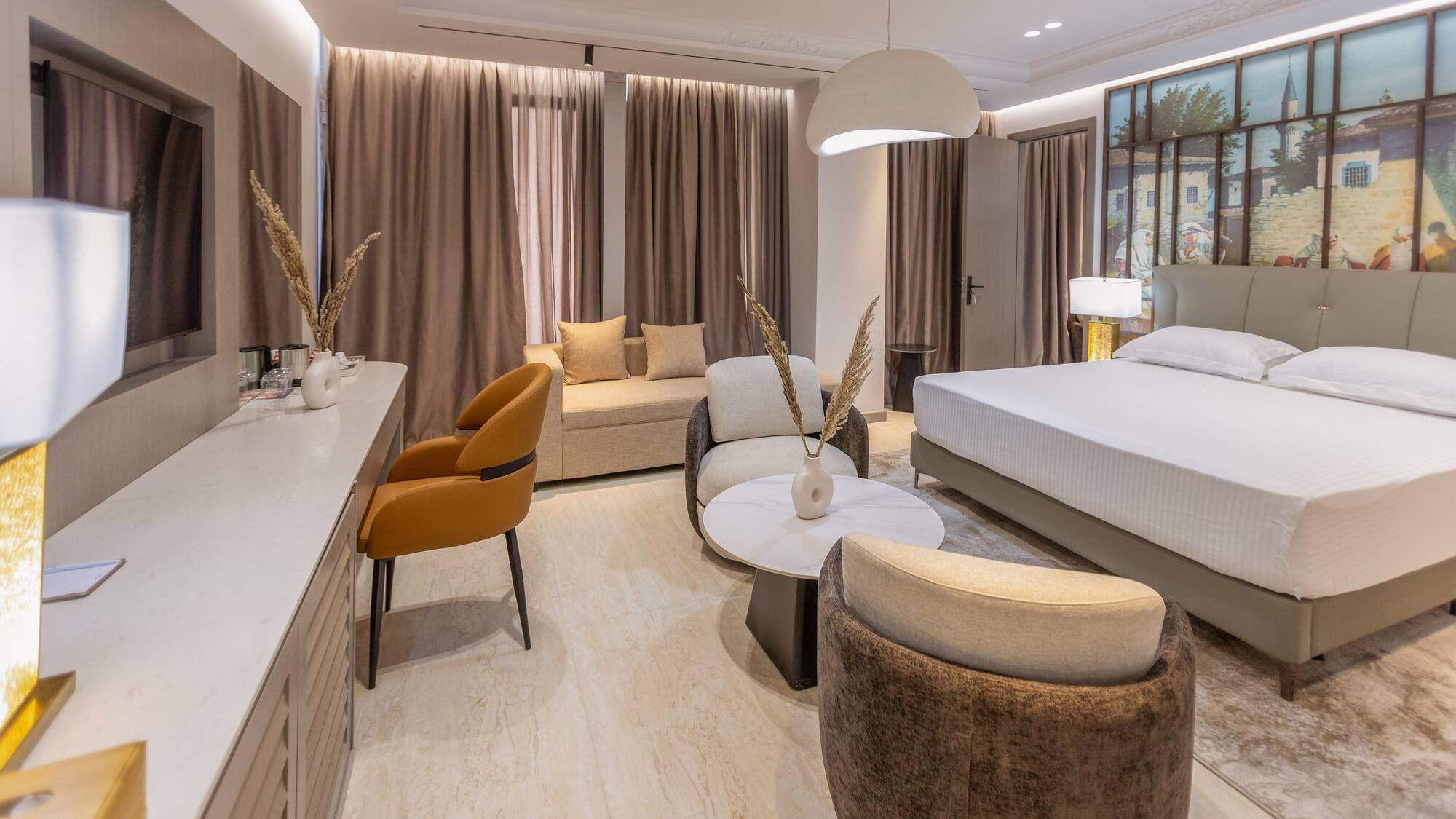 Modern hotel suite with king bed, cozy living area, and elegant neutral decor.