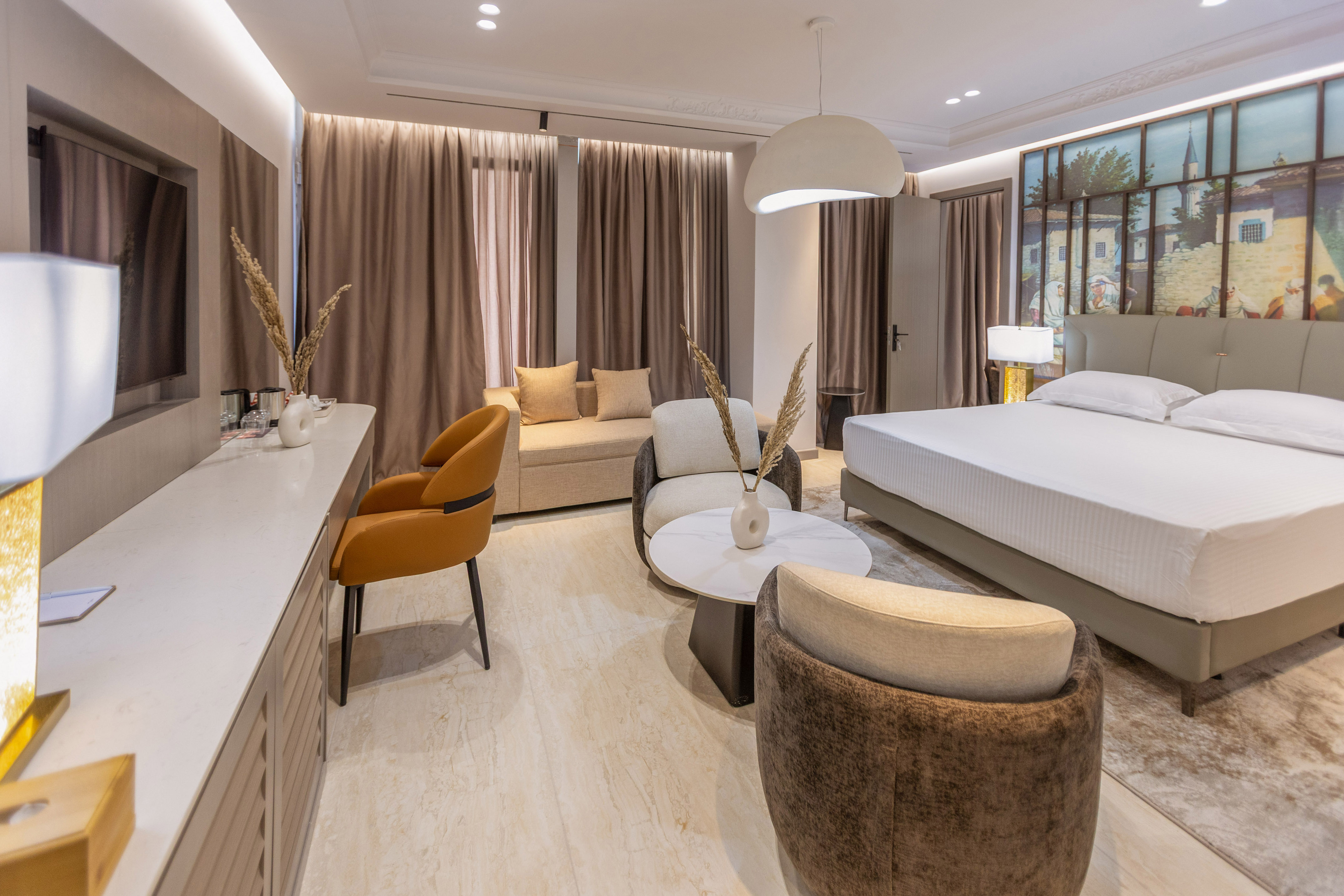 Modern hotel suite with king bed, cozy living area, and elegant neutral decor.