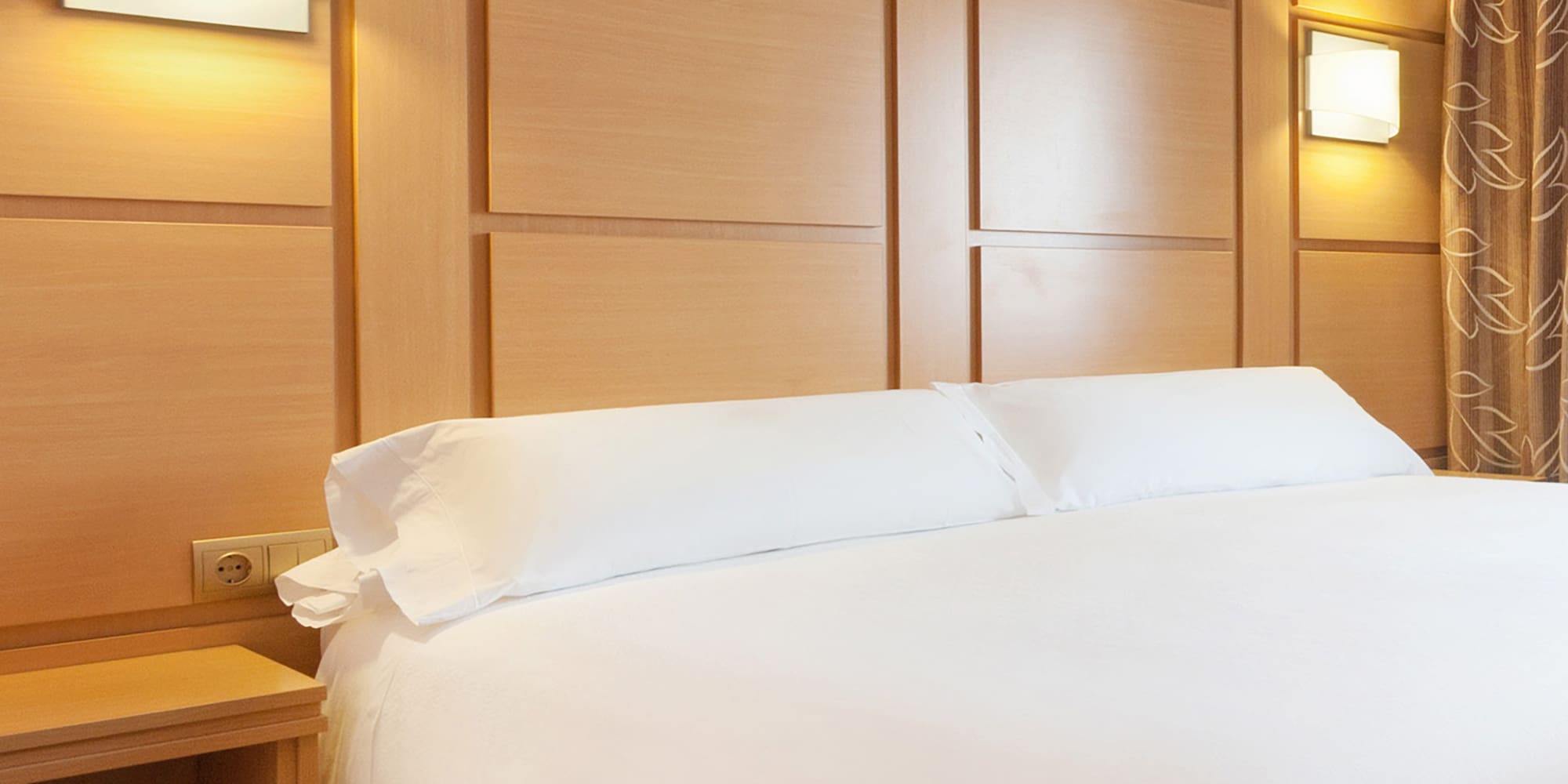 a bed with white sheets and a nightstand