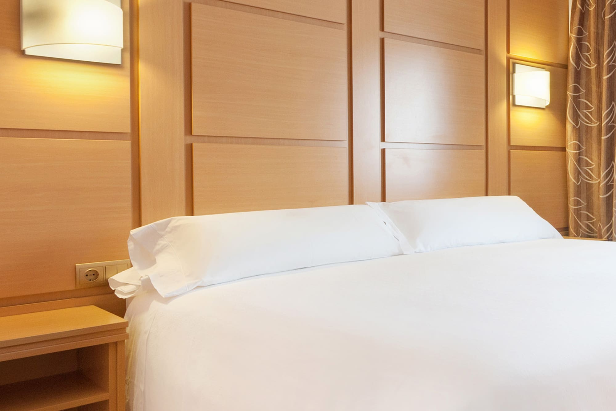 a bed with white sheets and a nightstand