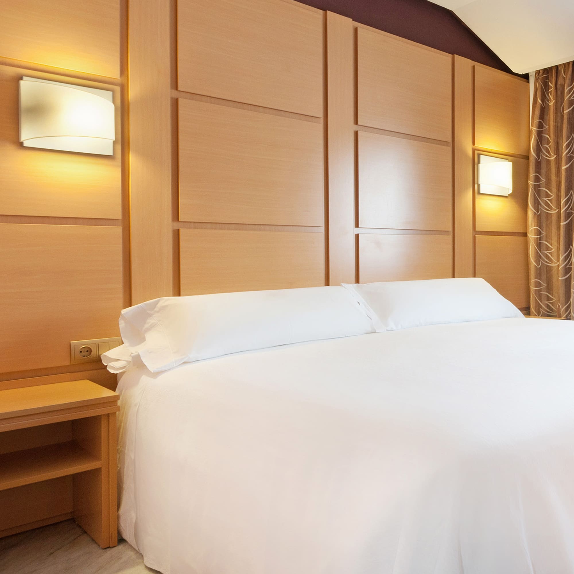 a bed with white sheets and a nightstand