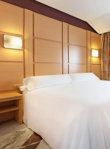 a bed with white sheets and a nightstand