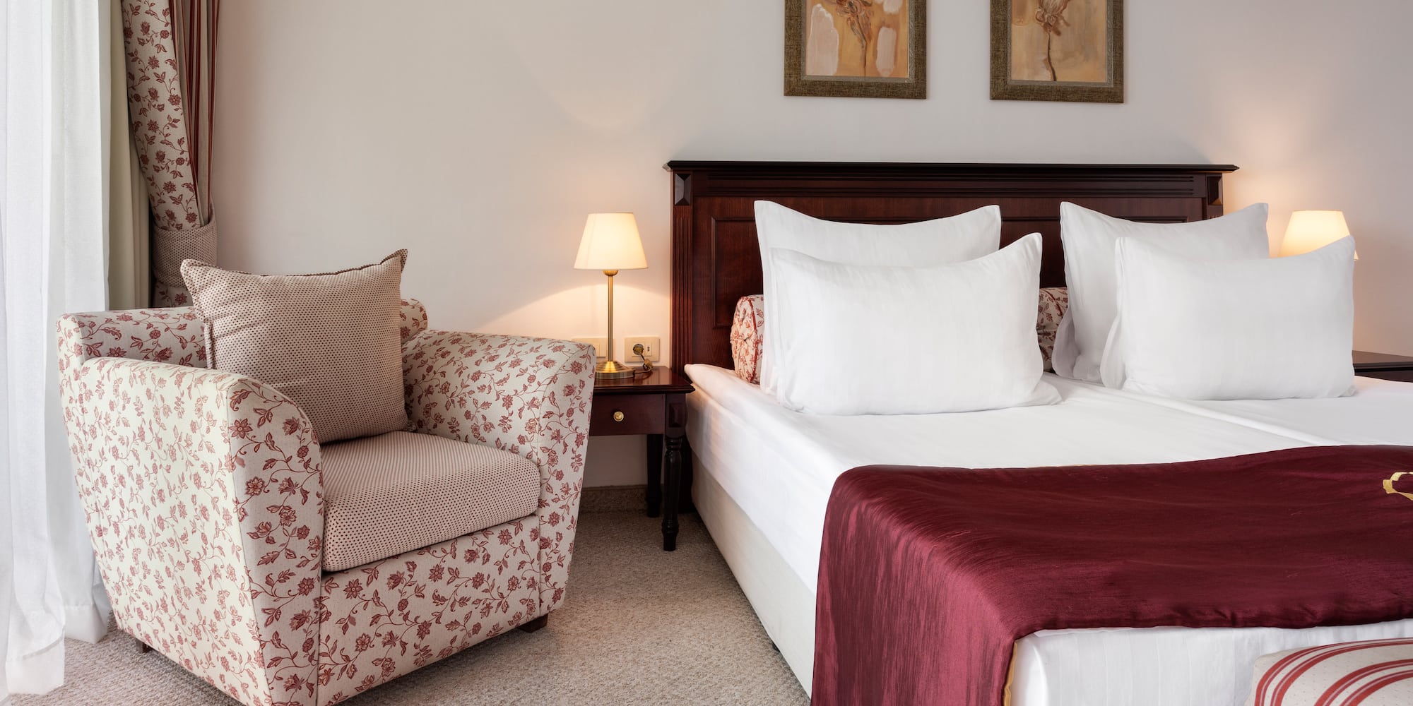 a bed with a red blanket and a chair in a room