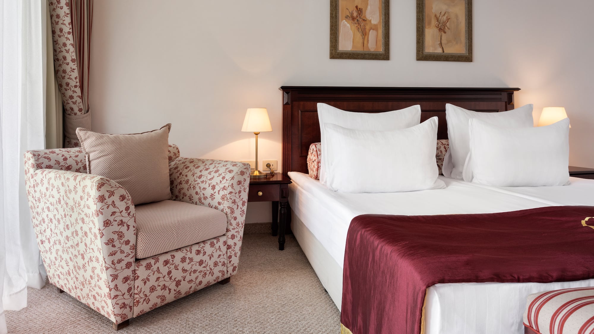 a bed with a red blanket and a chair in a room