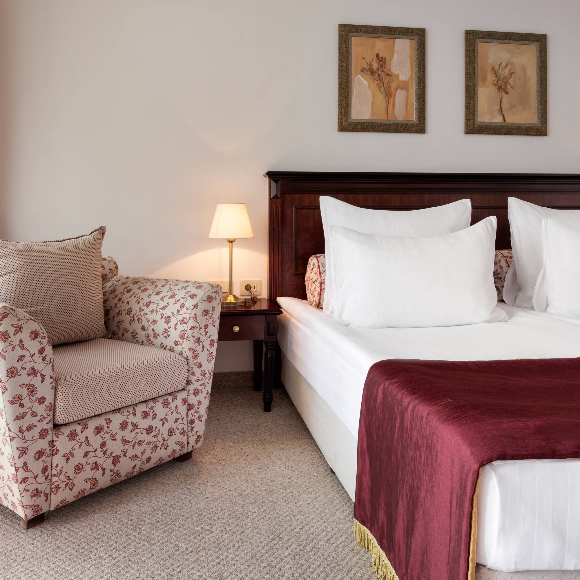 a bed with a red blanket and a chair in a room