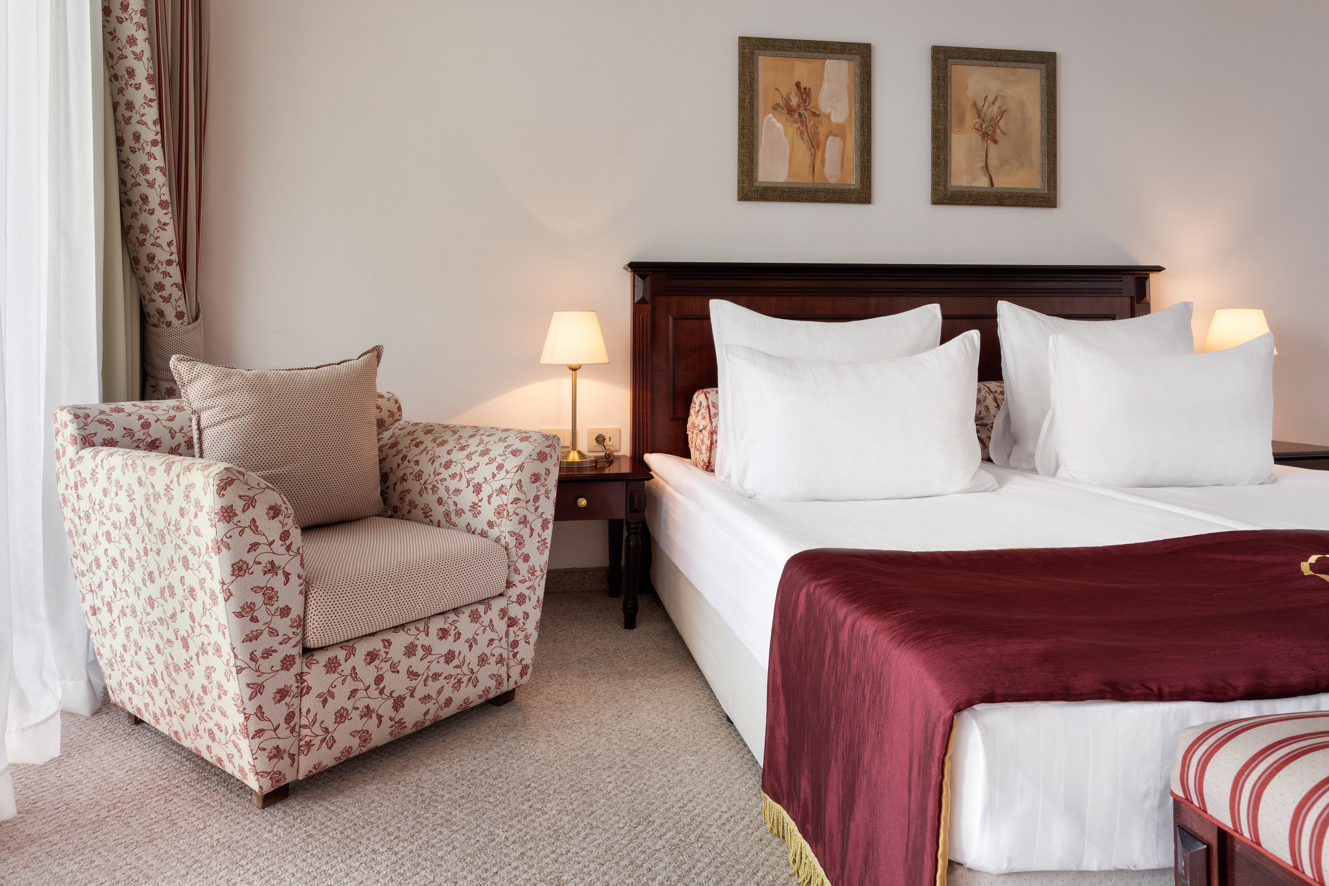 a bed with a red blanket and a chair in a room