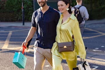 a man and woman walking on a street with shopping bags