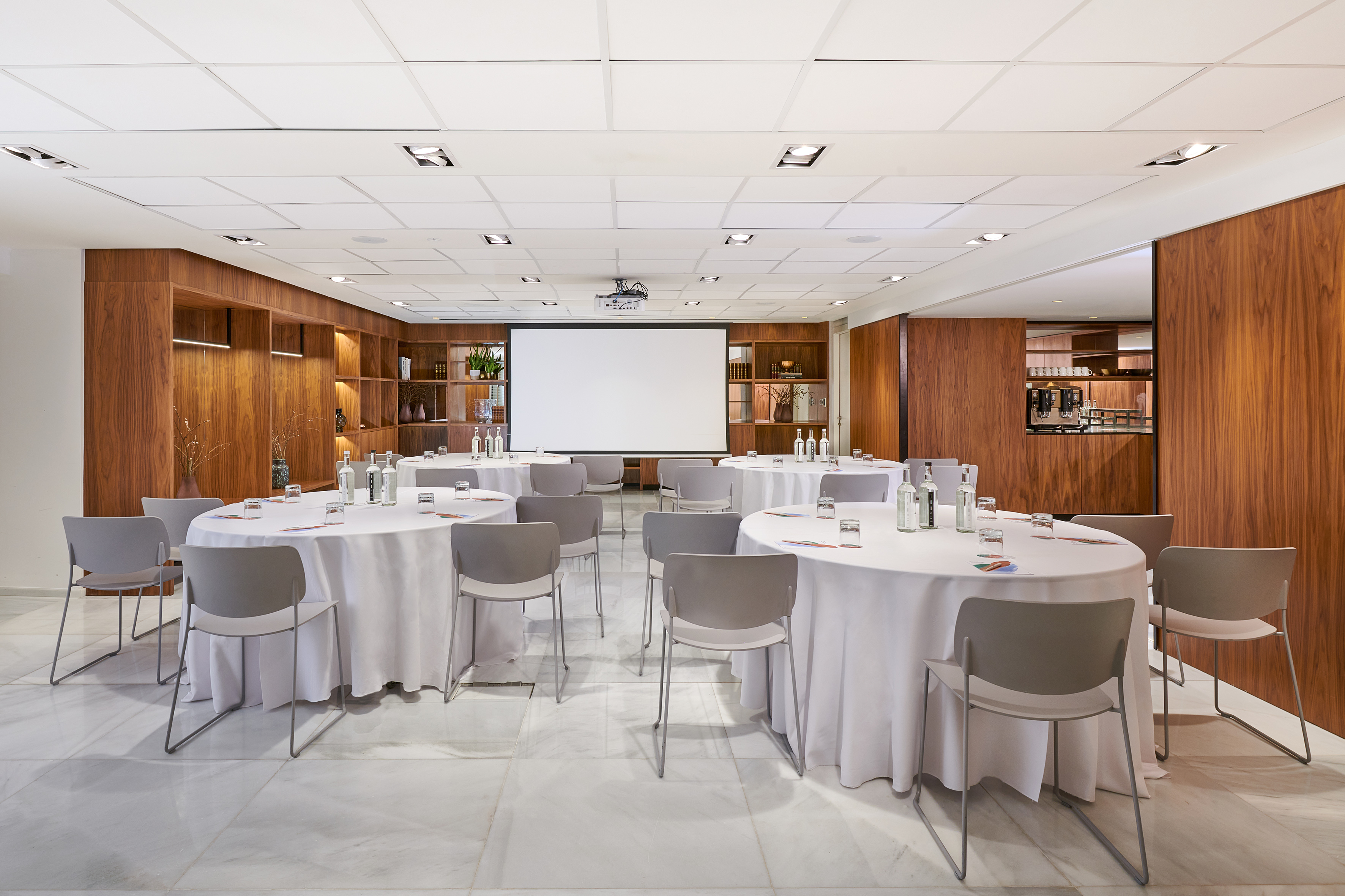 Modern conference room with round tables, projector, and wood-paneled walls.