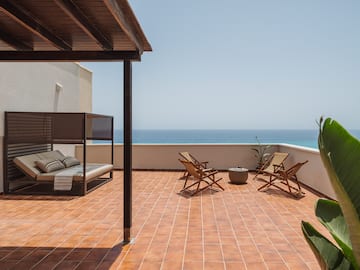 a deck with chairs and a fire pit on a sunny day