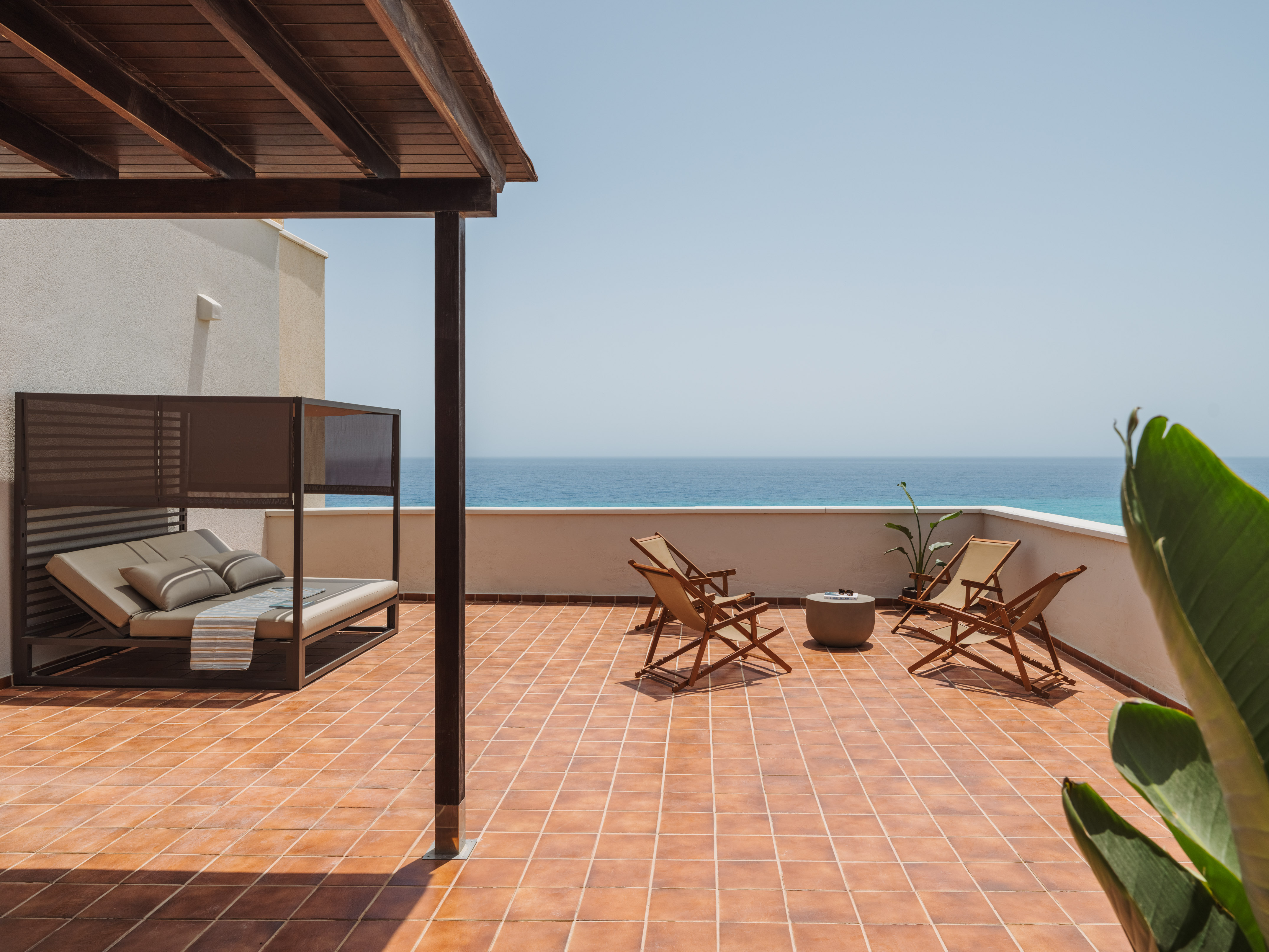 a deck with chairs and a fire pit on a sunny day