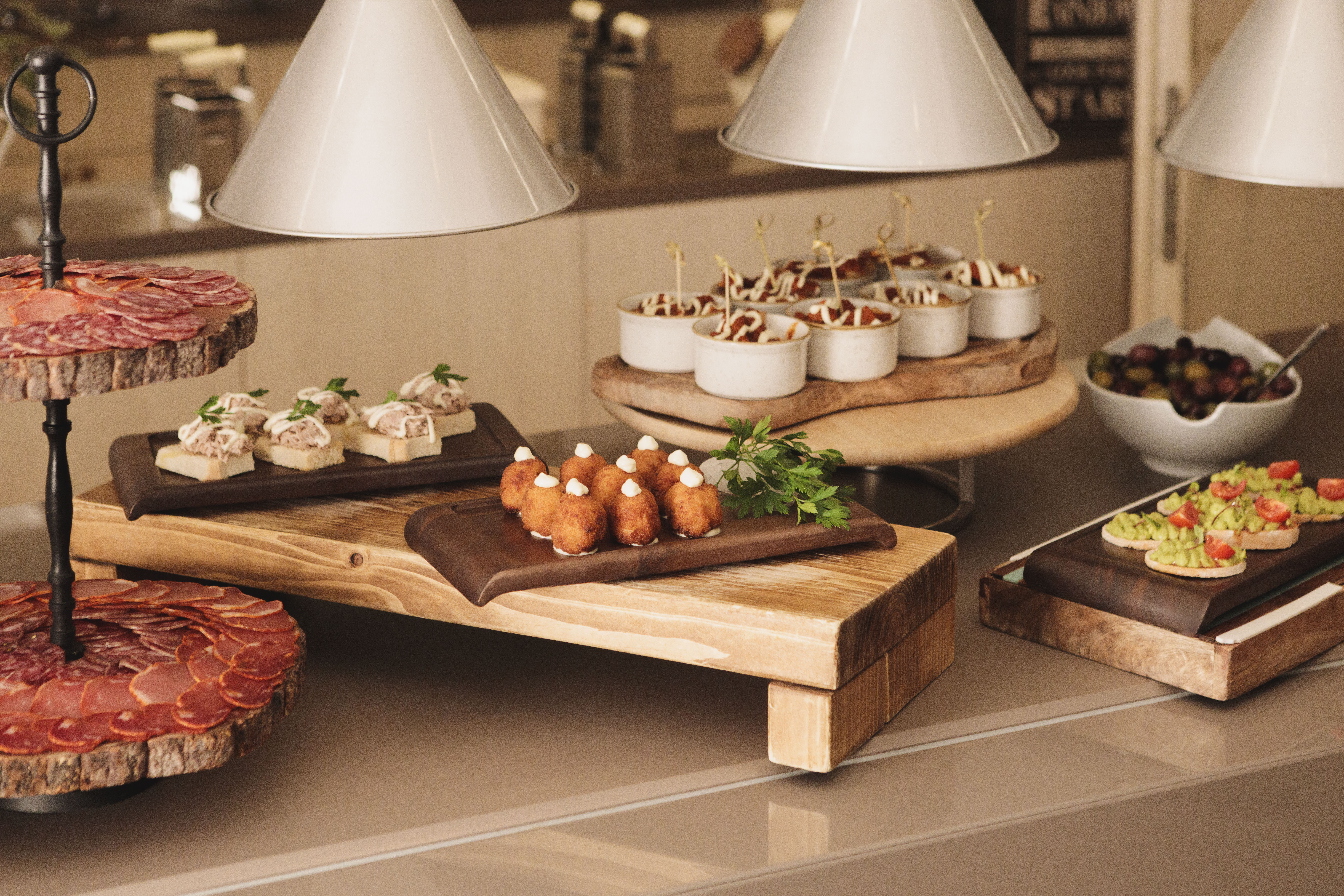 Buffet table with charcuterie, canapés, croquettes, and avocado bruschetta.