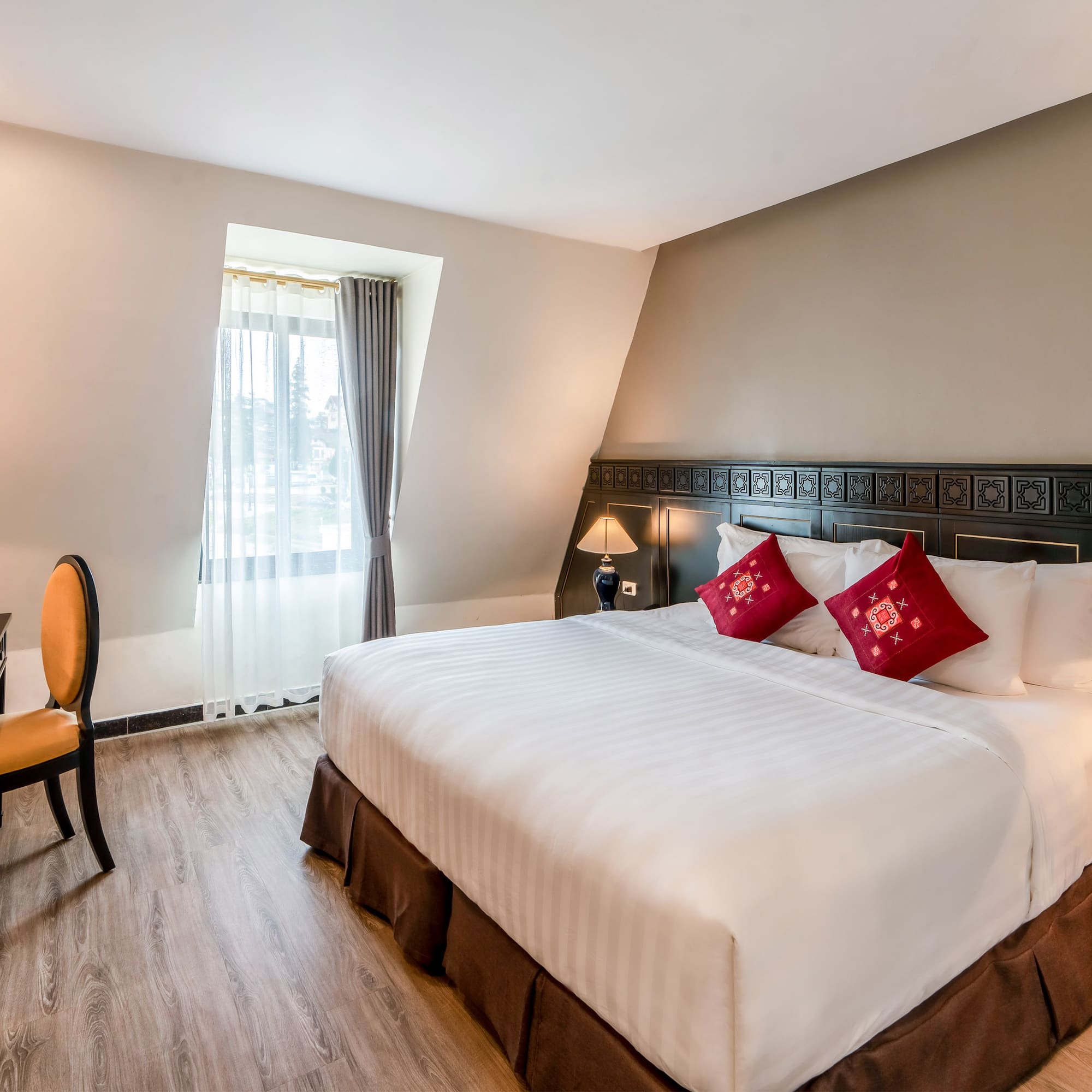 a bed with red pillows and a chair in a room