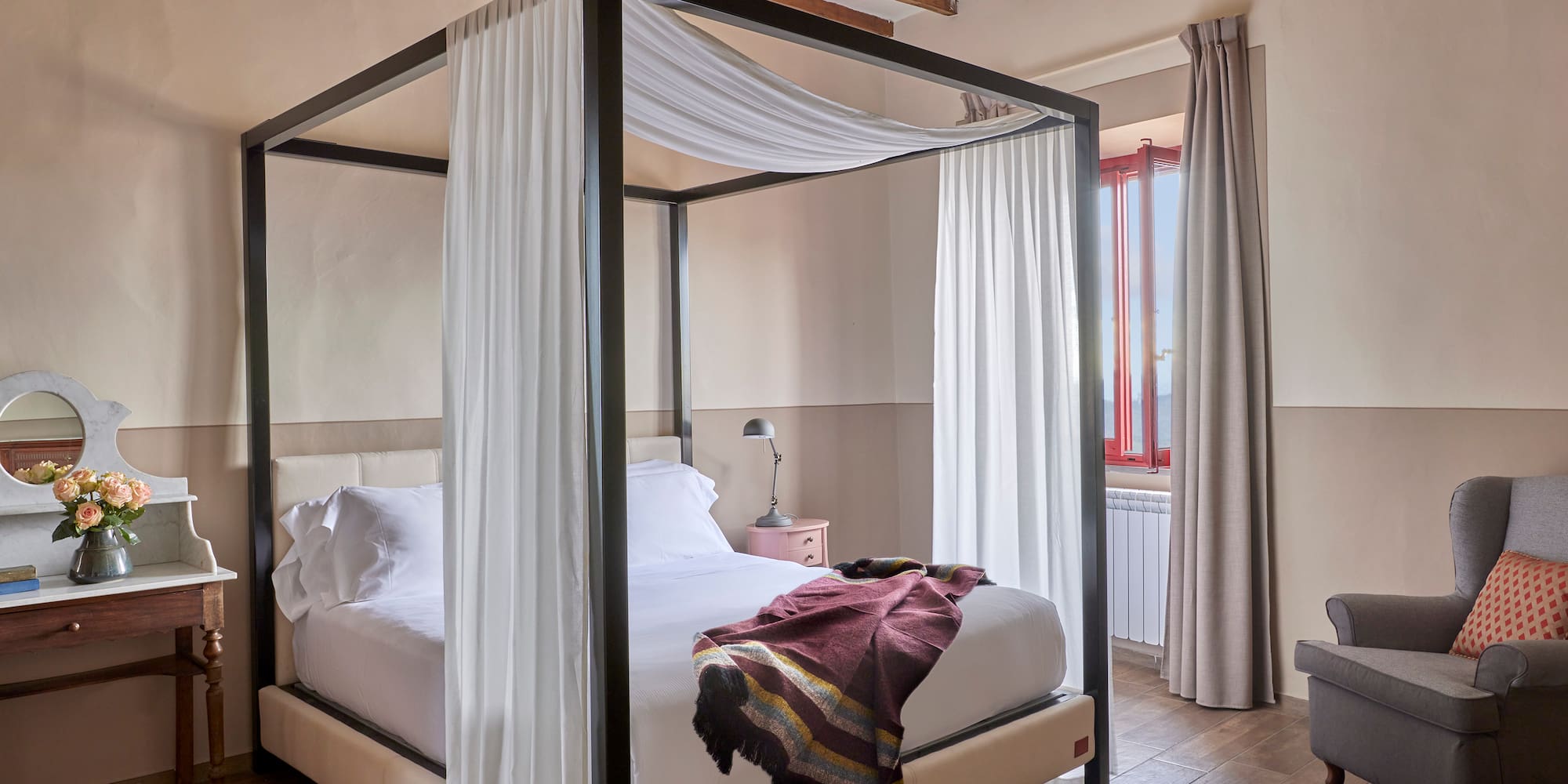 a bed with white curtains and a wood floor