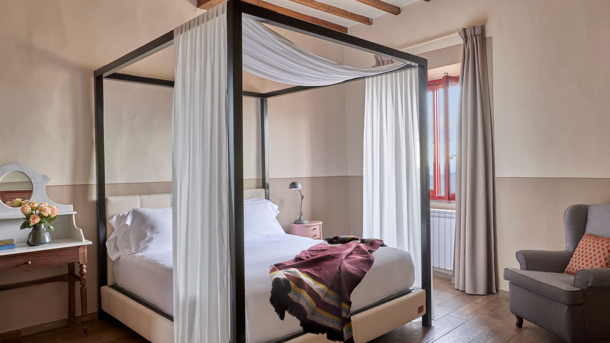 a bed with white curtains and a wood floor