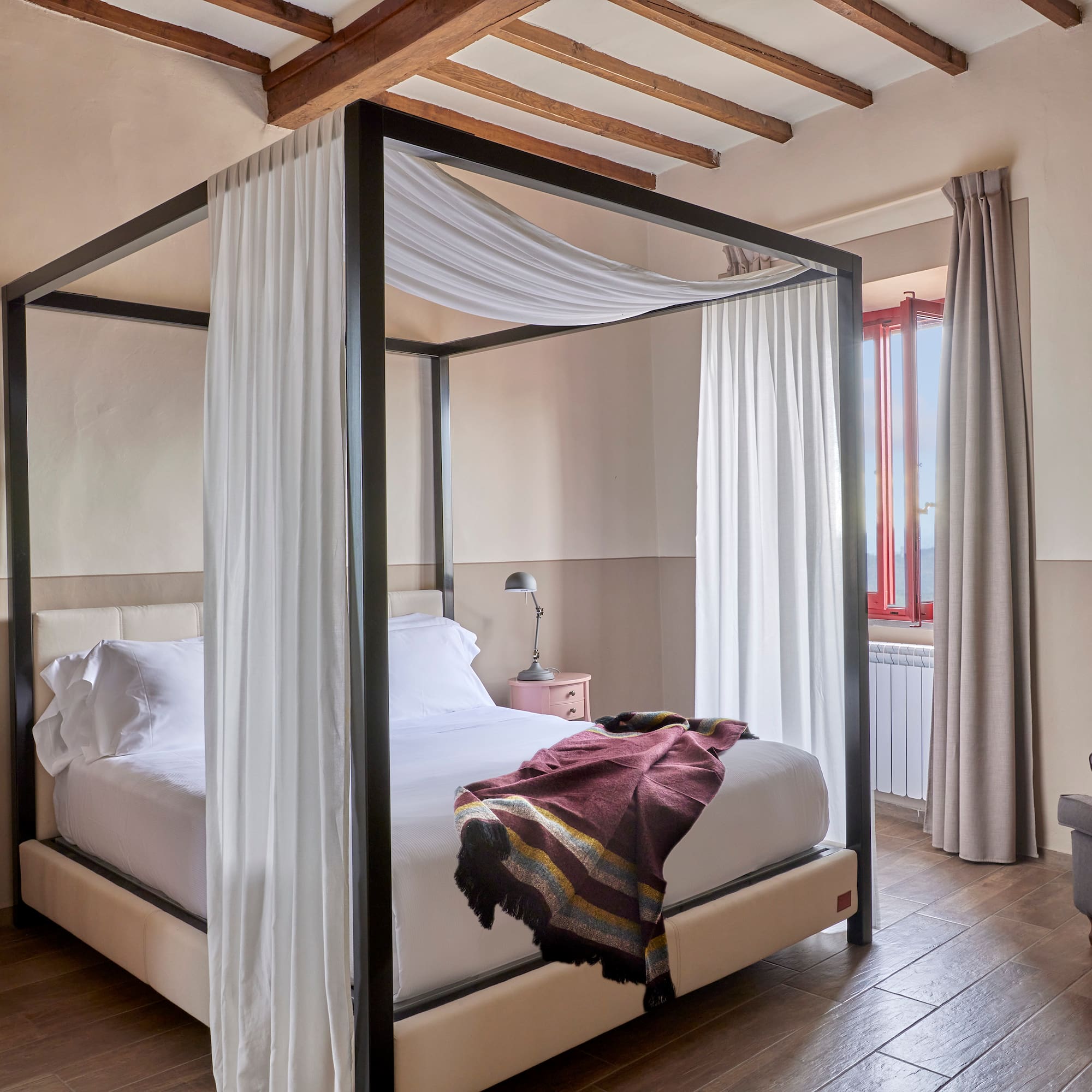 a bed with white curtains and a wood floor