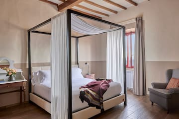 a bed with white curtains and a wood floor