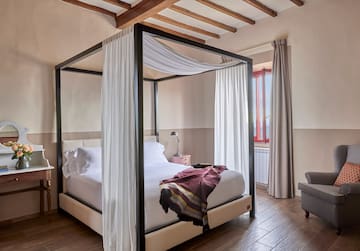 a bed with white curtains and a wood floor