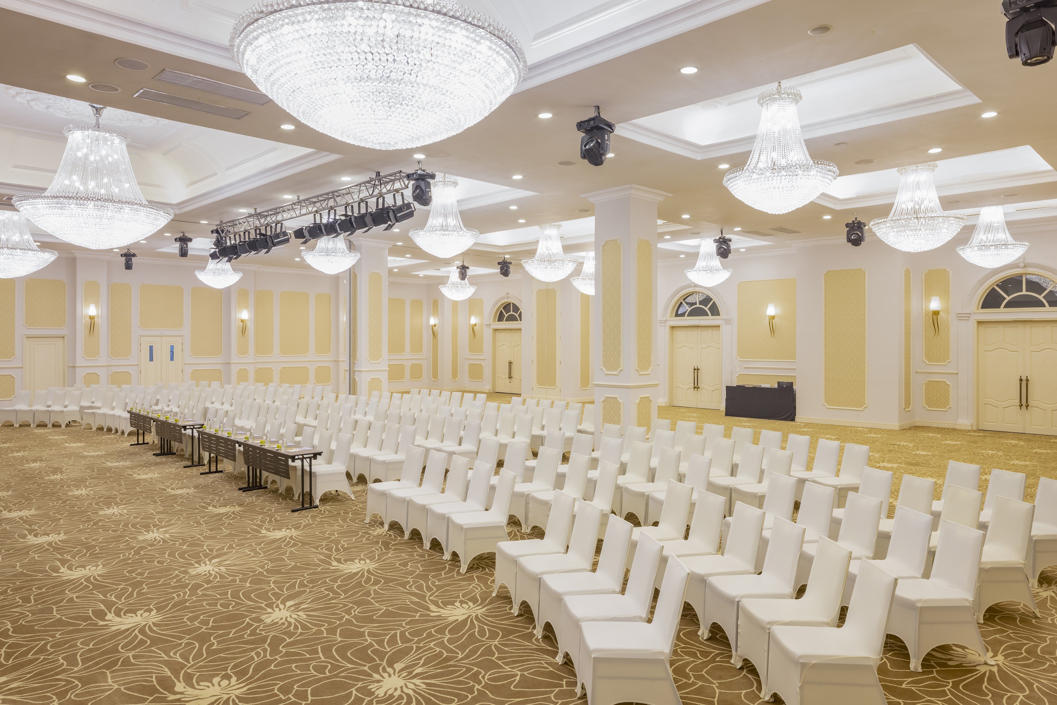 Elegant conference room with rows of white chairs and crystal chandeliers.