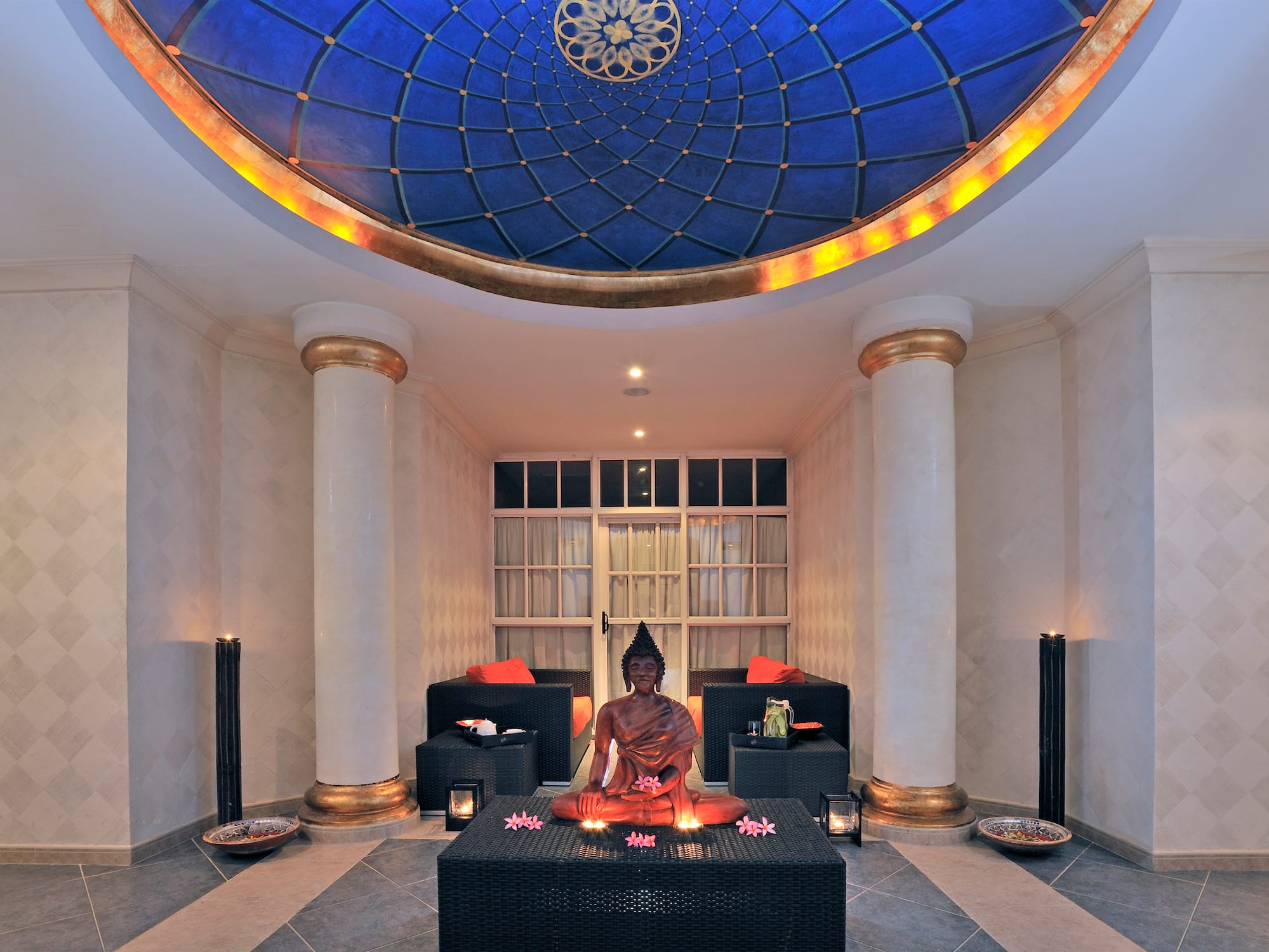 a statue of a buddha sitting on a table in a room with blue ceiling