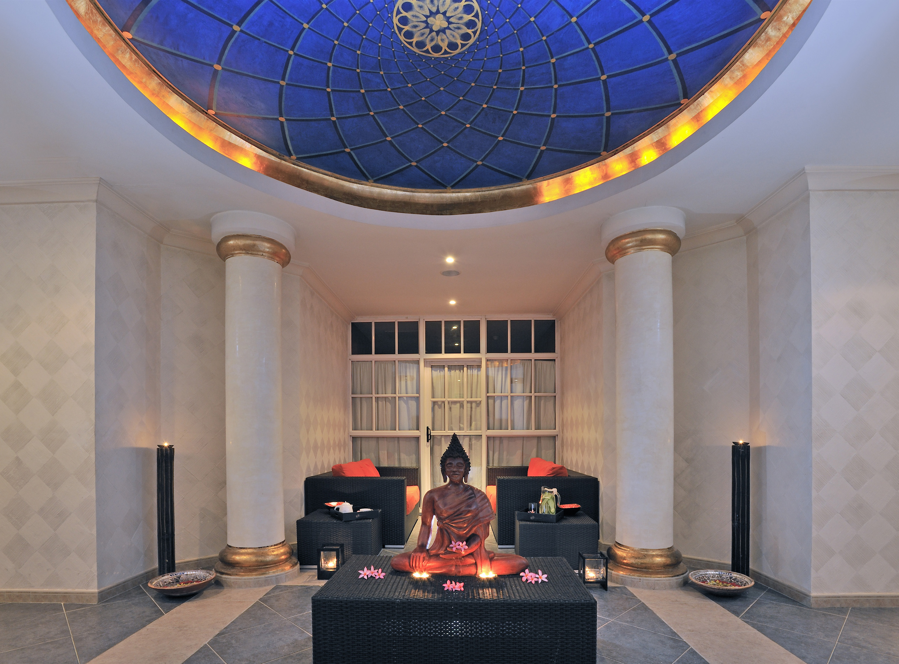 a statue of a buddha sitting on a table in a room with blue ceiling