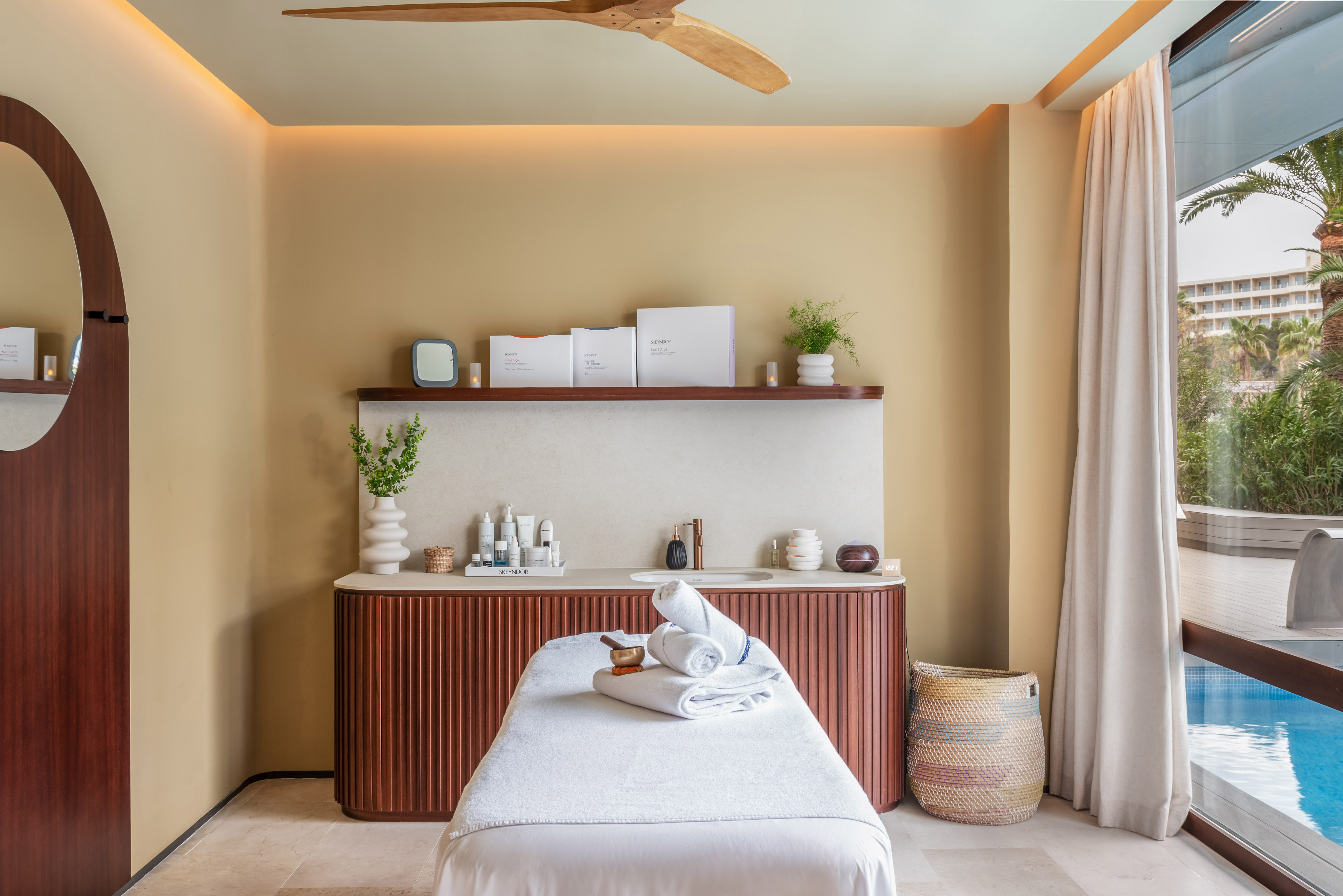 Luxury spa massage room with Skeyndor products, treatment table, and pool view.