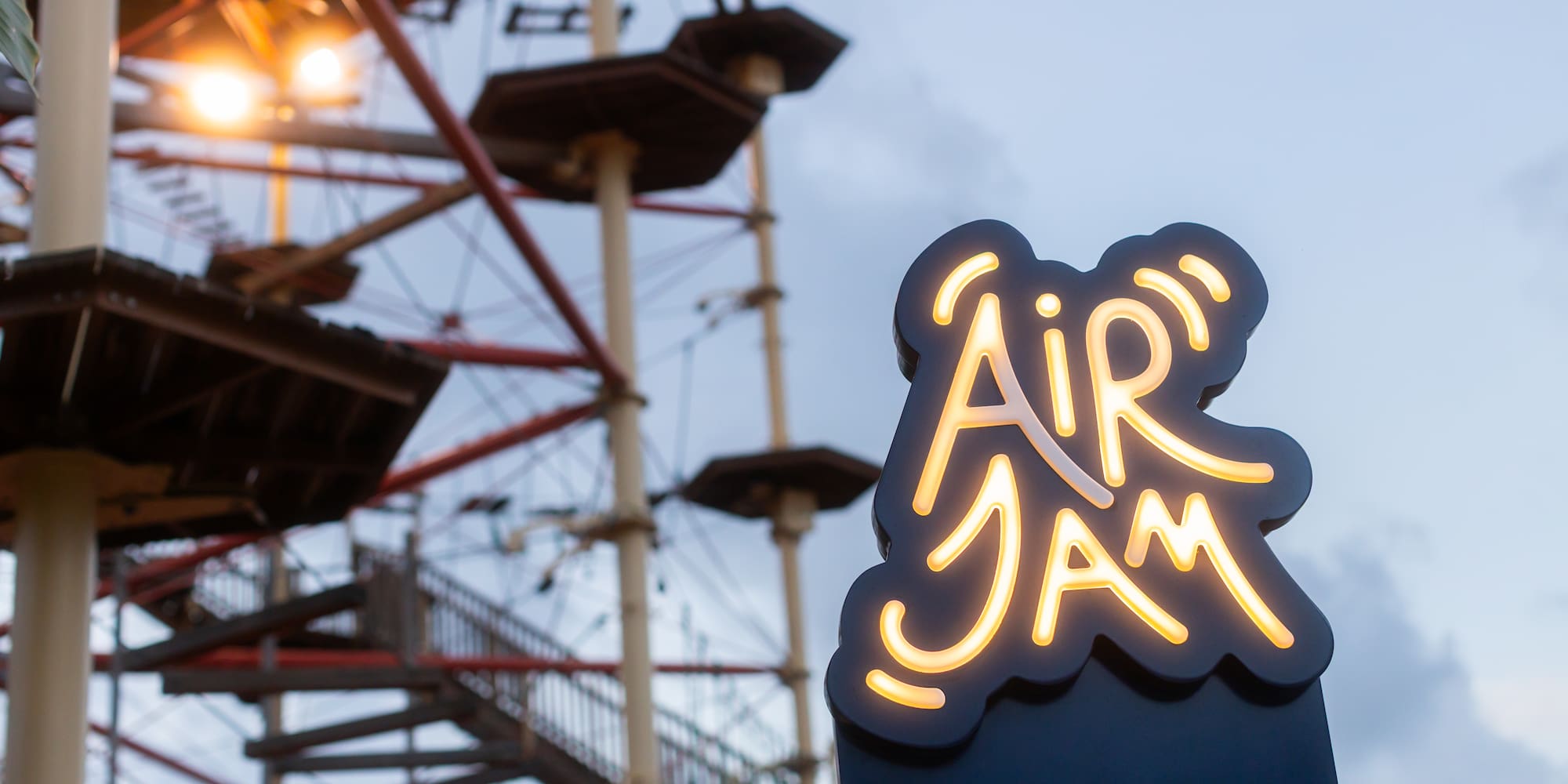 a sign with a lit up sign in front of a ferris wheel