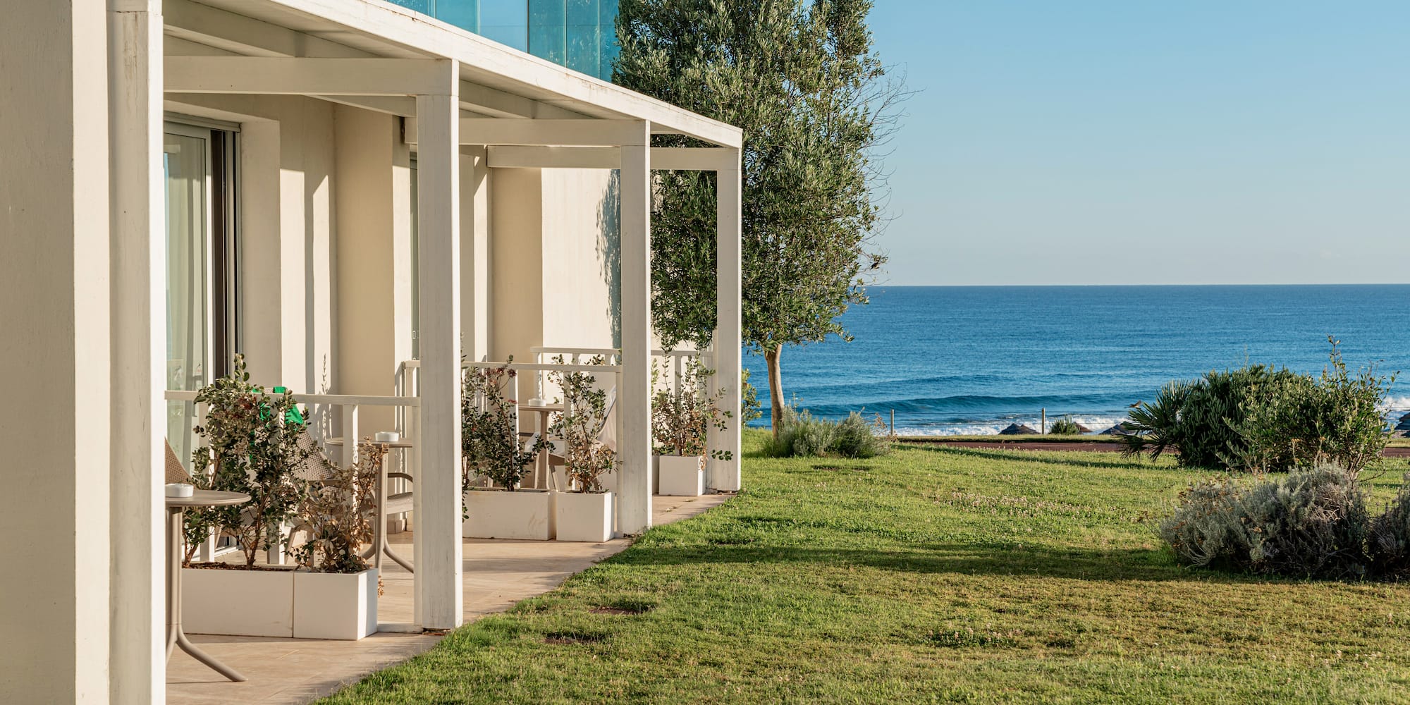 a white building with a lawn and a fence by the ocean