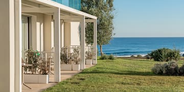 a white building with a lawn and a fence by the ocean