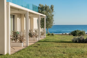 a white building with a lawn and a fence by the ocean