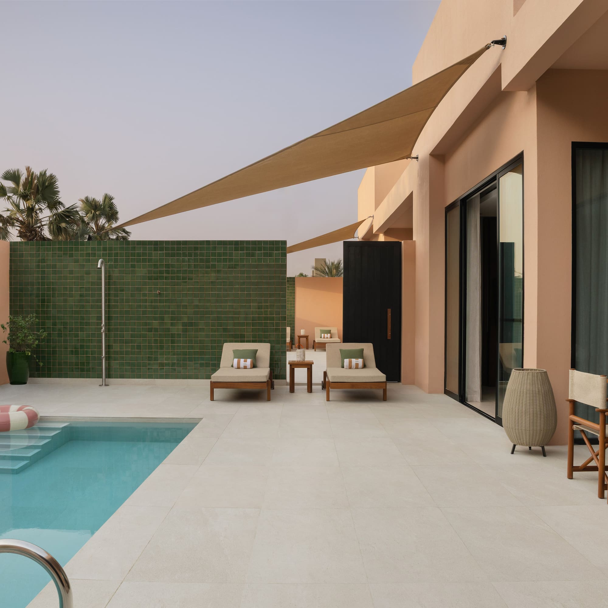 a pool and chairs outside of a house