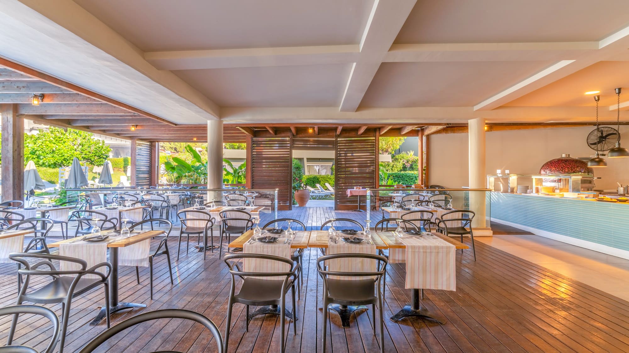 Al fresco resort restaurant with wooden deck, set tables, and a buffet.