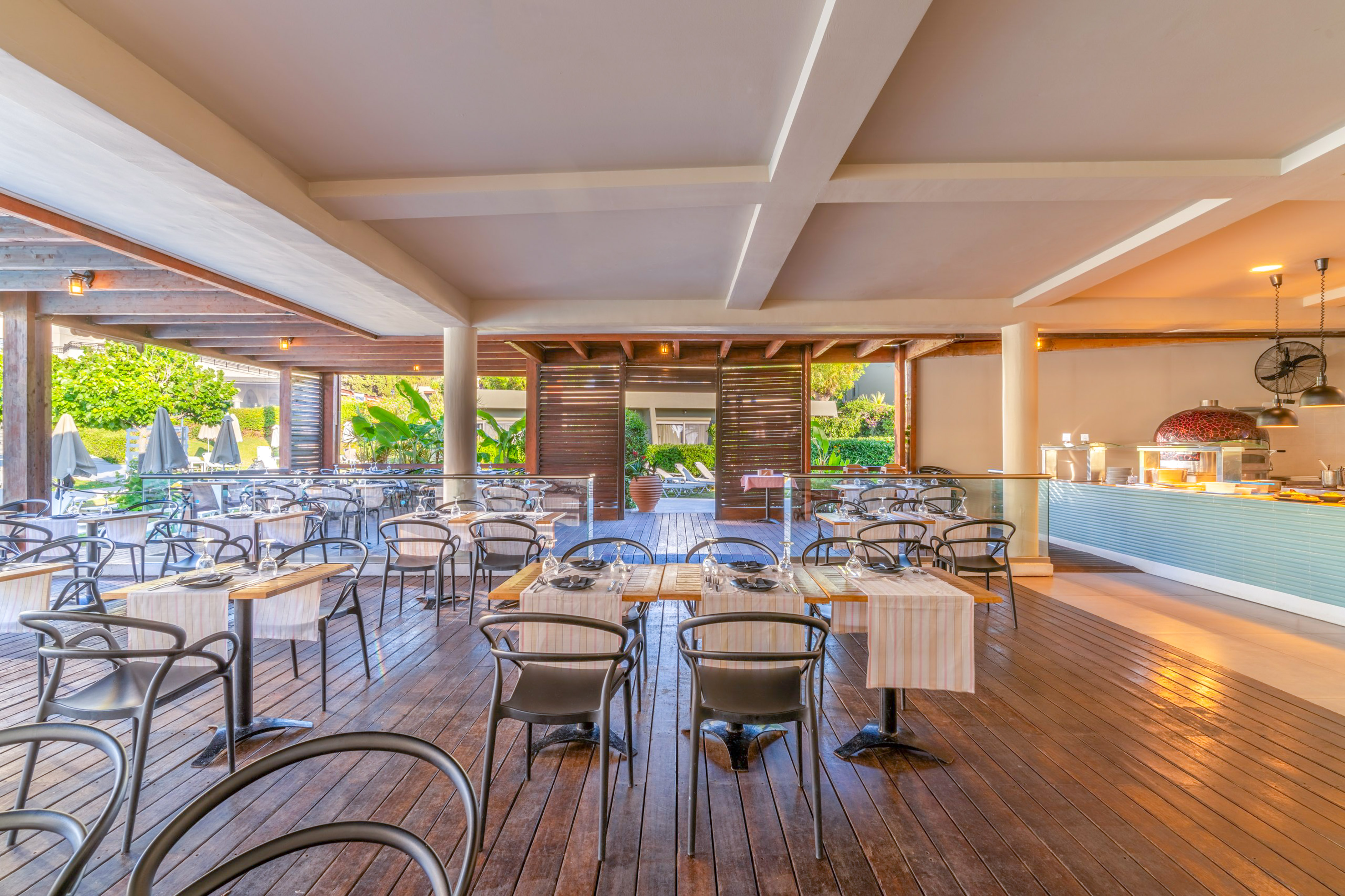 Al fresco resort restaurant with wooden deck, set tables, and a buffet.