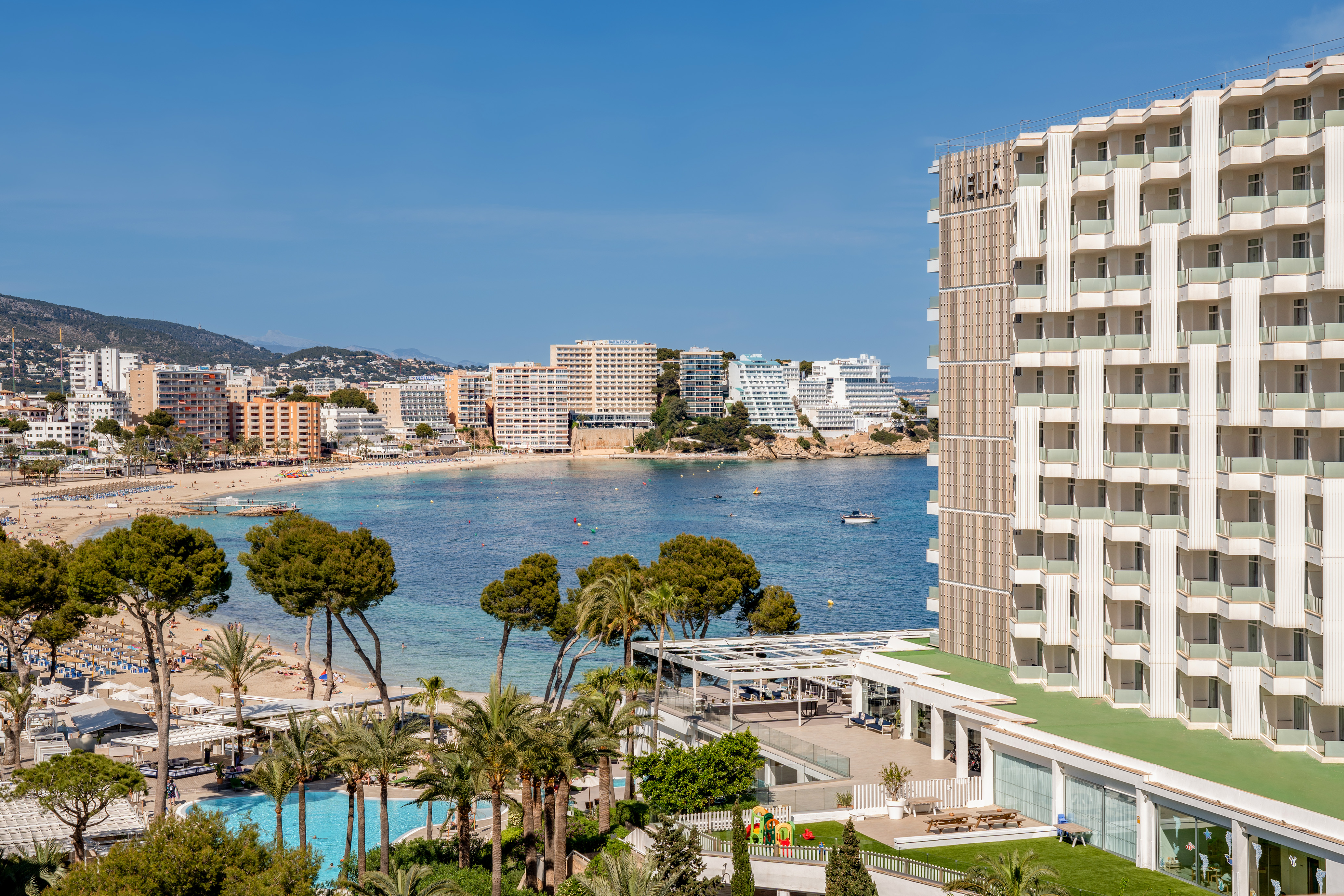 Meliá Calvià Beach resort with pool, palm trees, and scenic bay view.