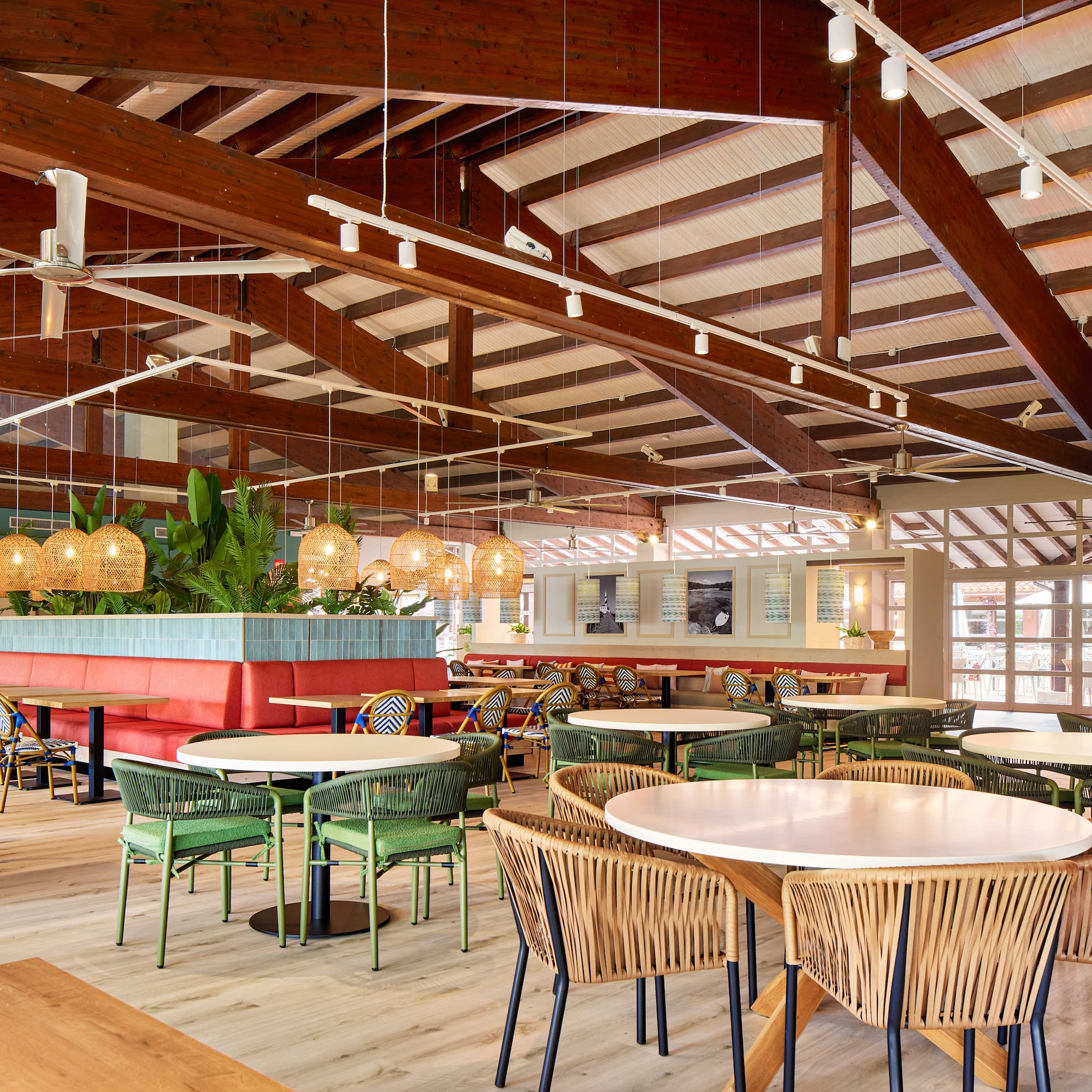 Modern tropical restaurant with wooden beams, wicker lights, and varied seating.