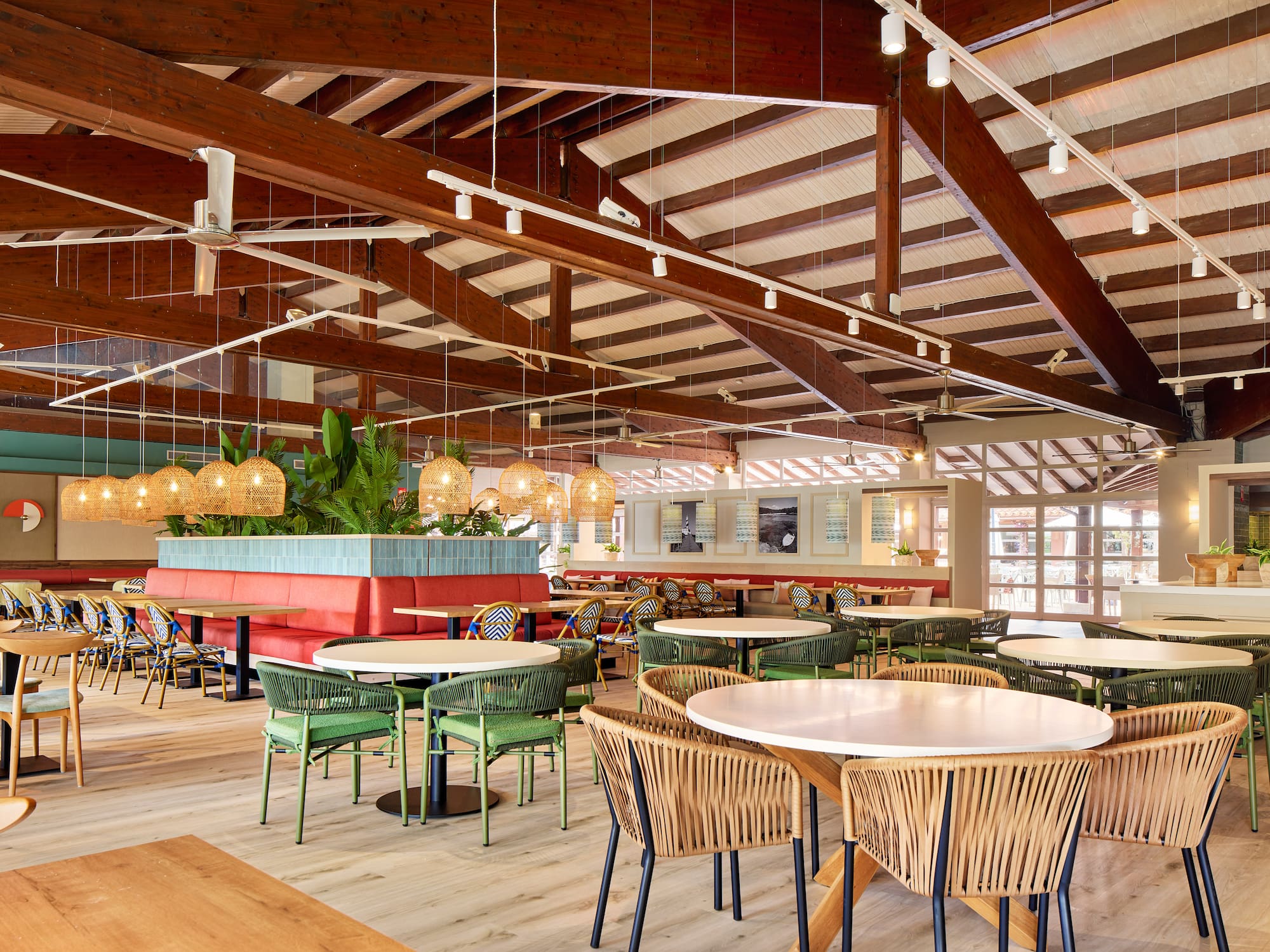 Modern tropical restaurant dining, wicker chairs, red booths, high wood ceiling.