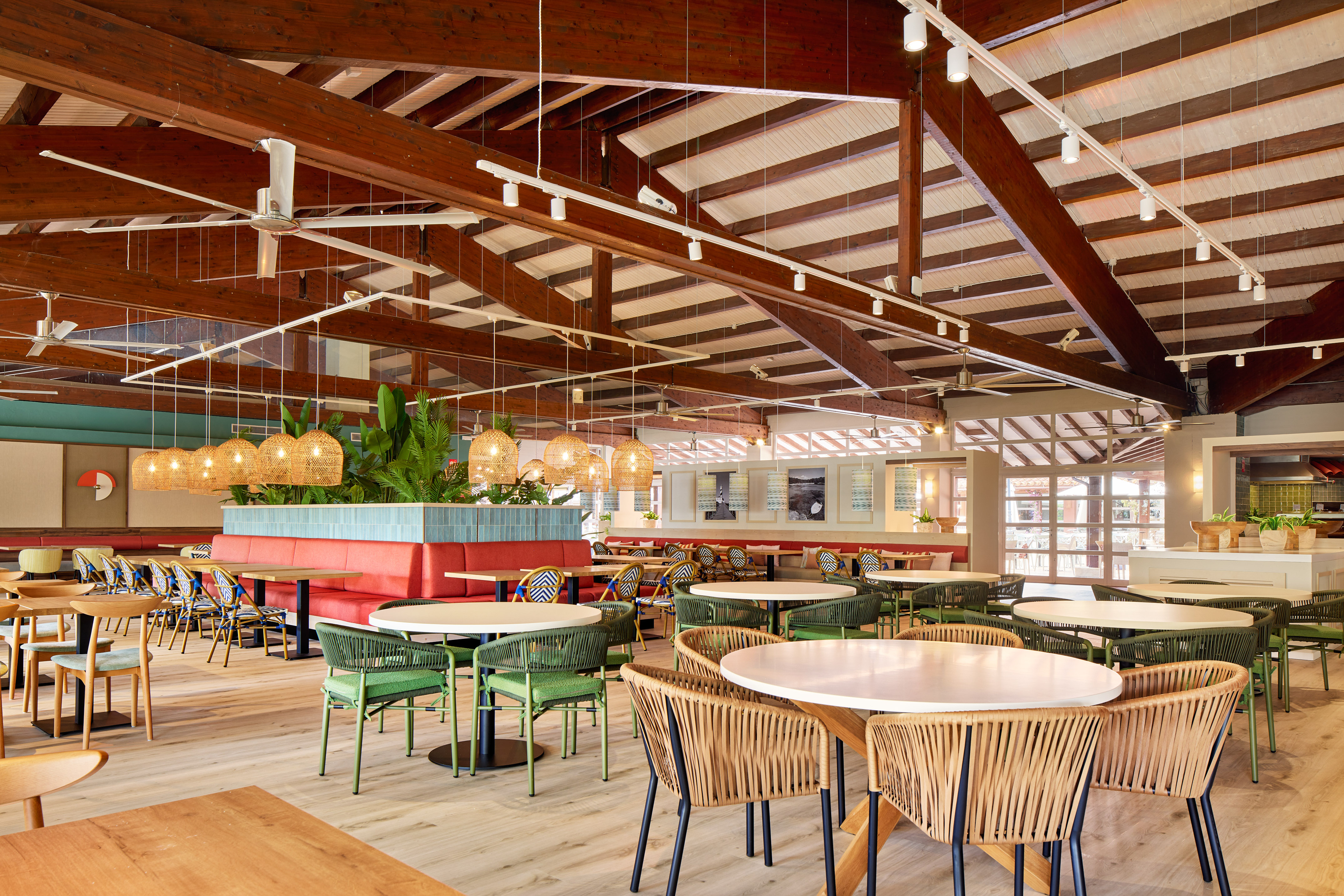 Modern tropical restaurant dining, wicker chairs, red booths, high wood ceiling.